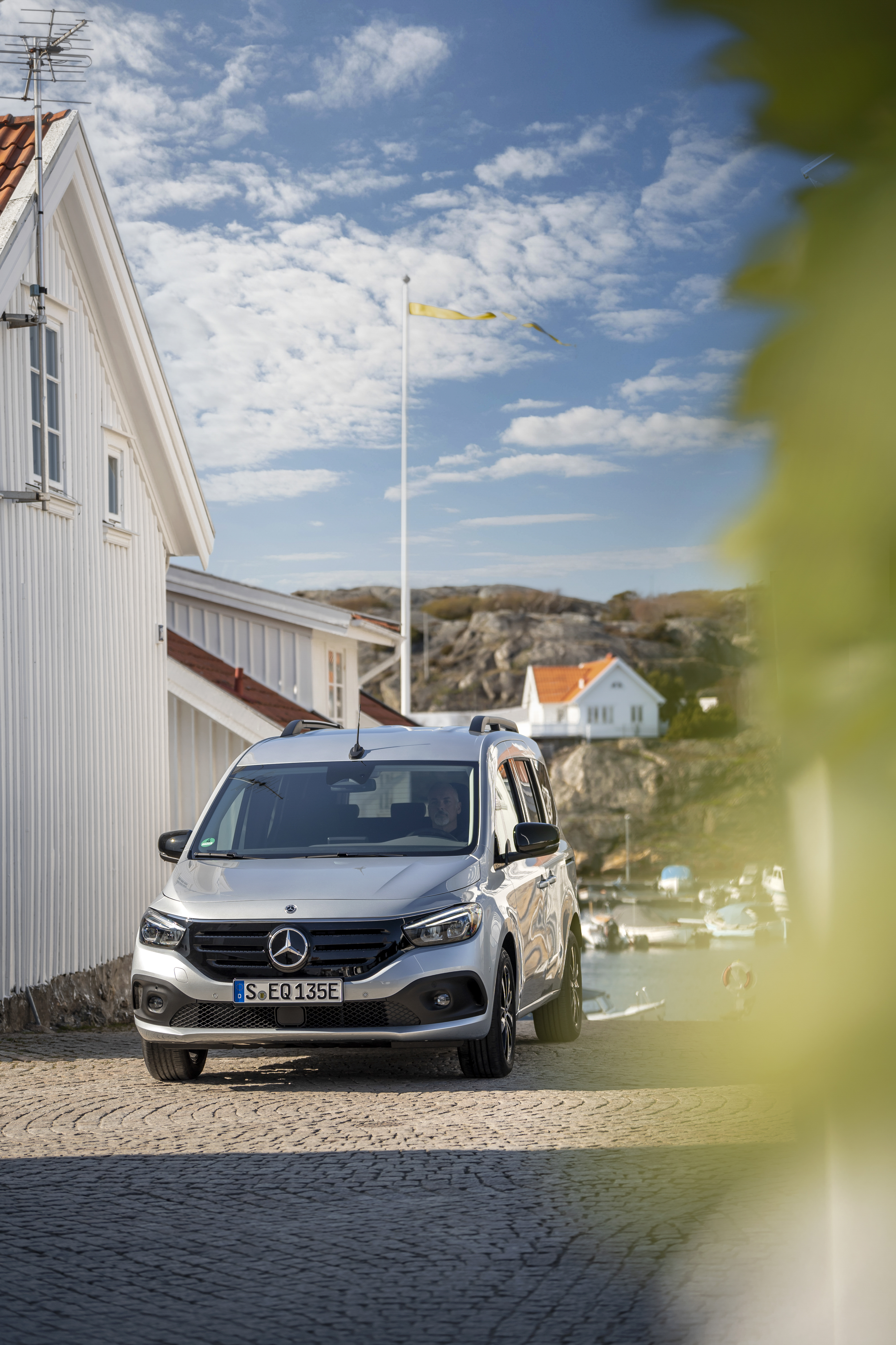 Ein silberner Mercedes-Benz EQT parkt neben einem Haus