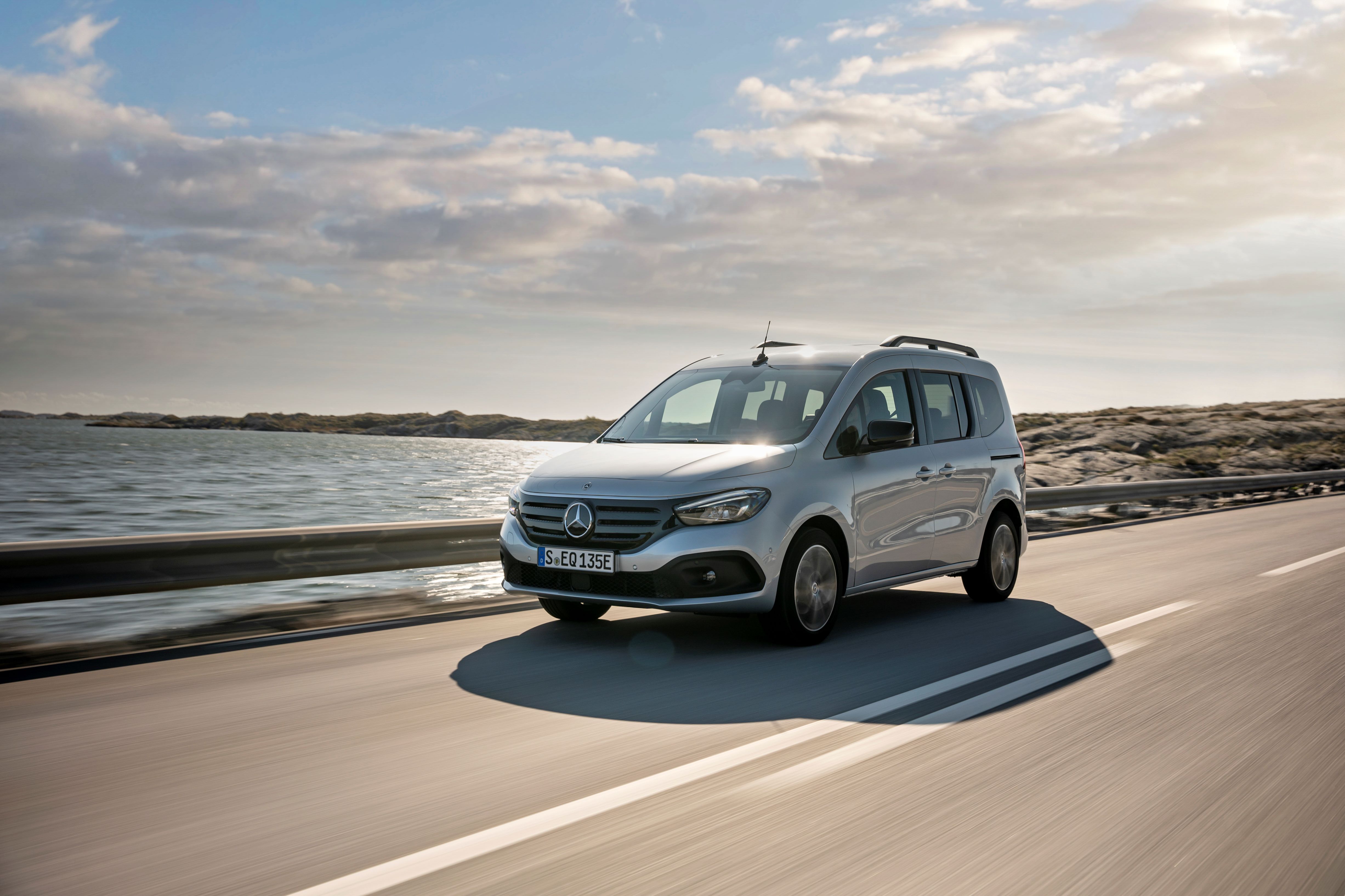 Ein silberner Mercedes-Benz EQT fährt auf einer Küstenstraße
