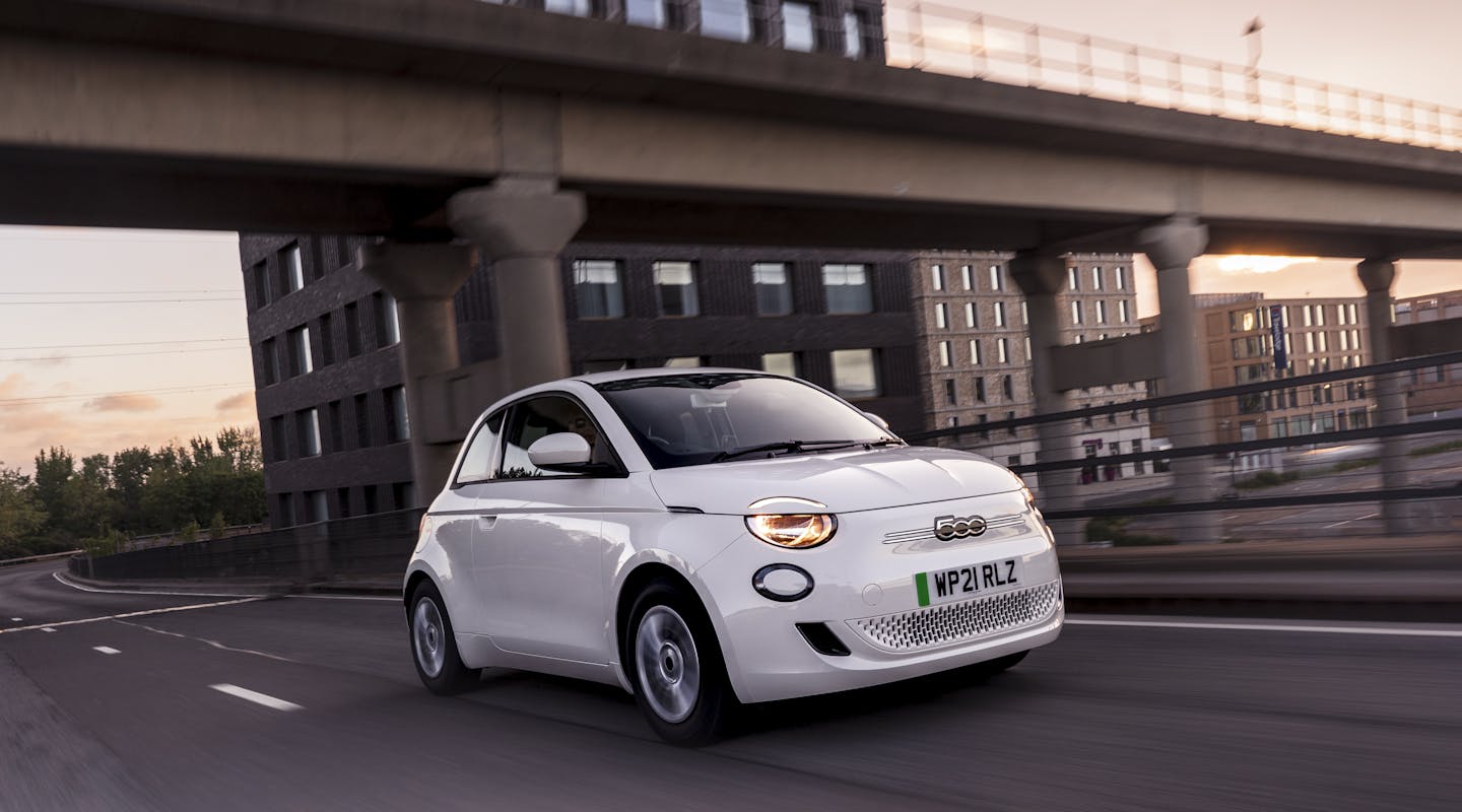 ein weißer Fiat 500e fährt durch eine Stadt