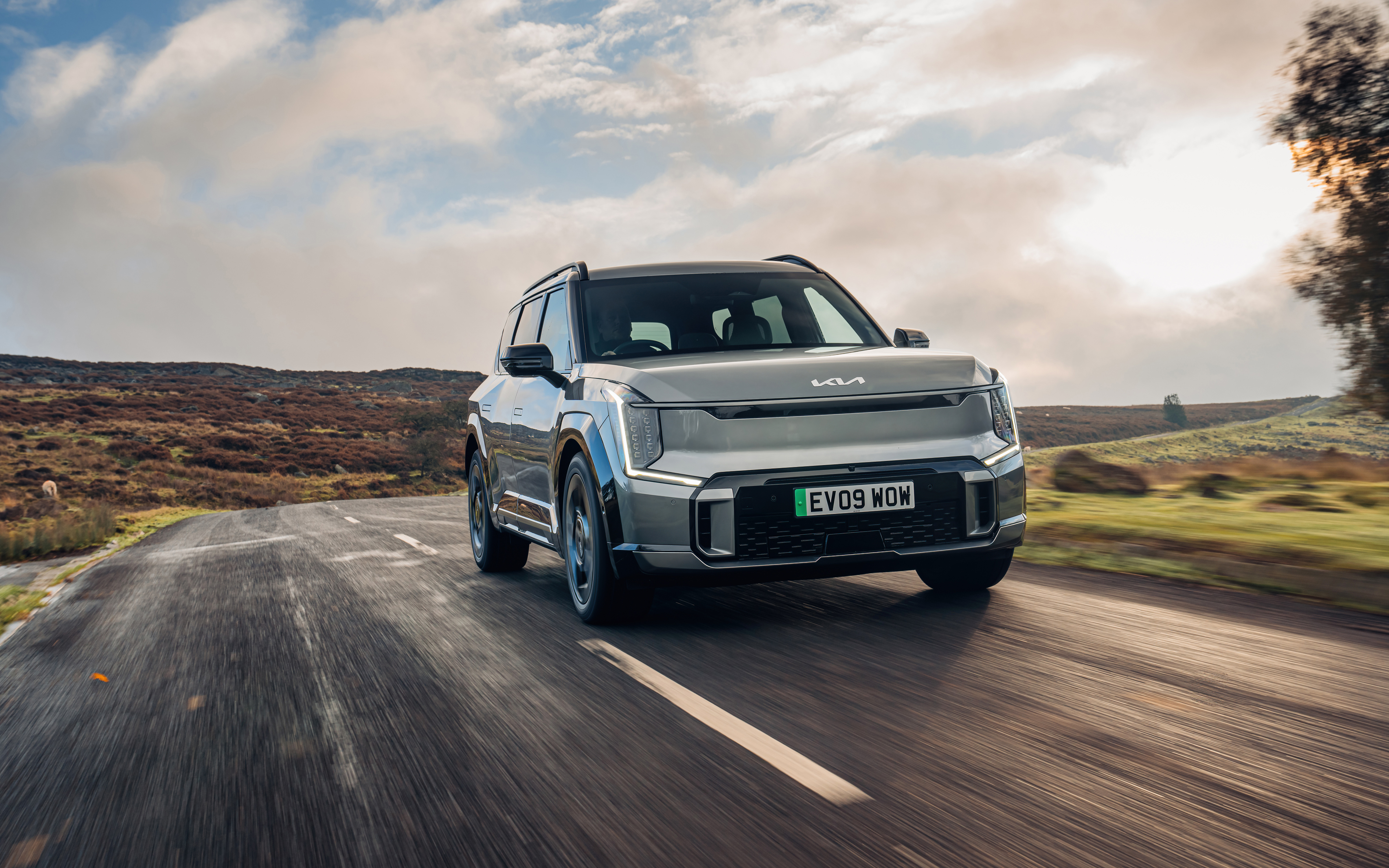 Ein grauer Kia EV9 fährt auf einer Landstraße