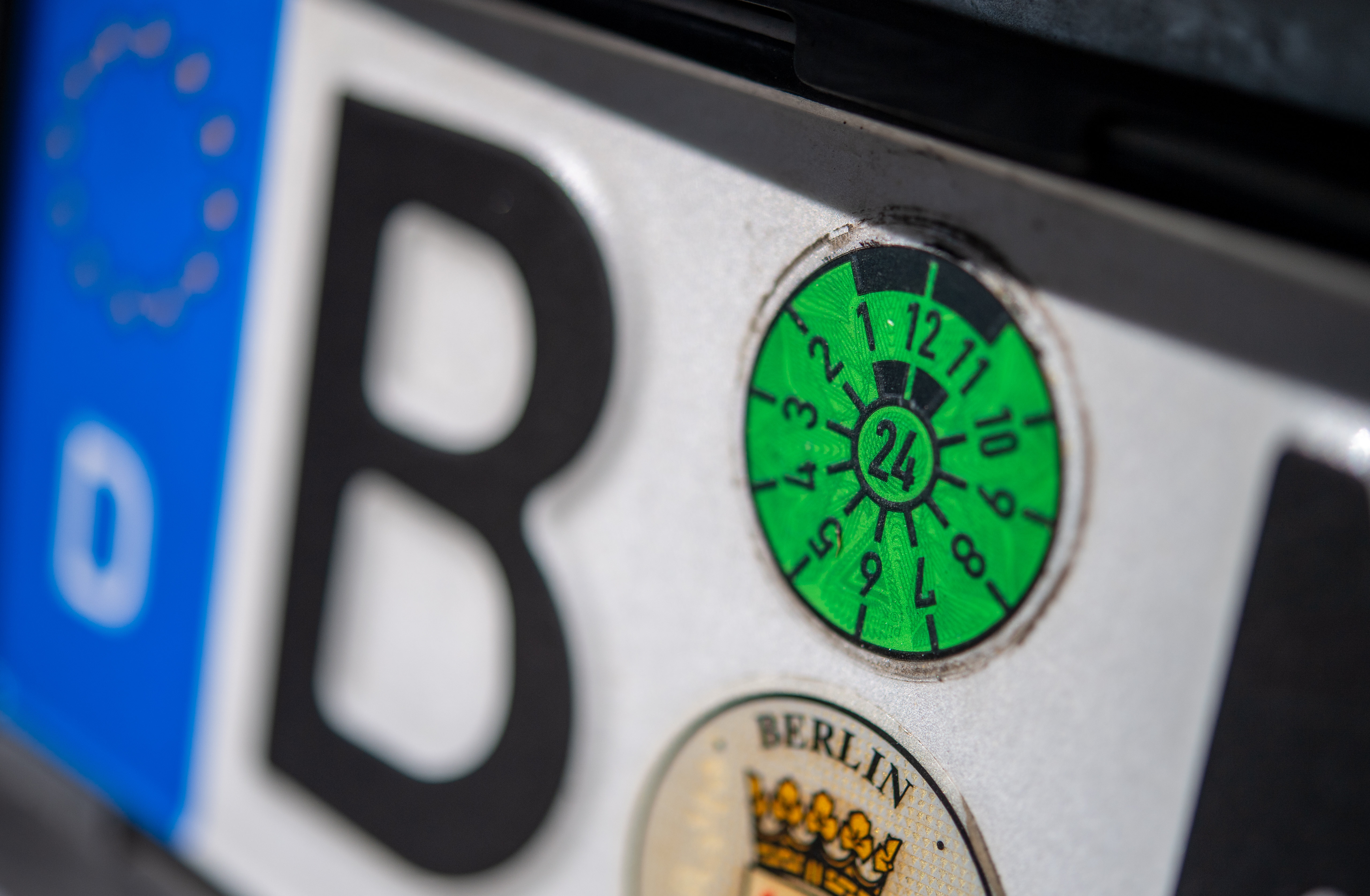 Großaufnahme einer HU-Plakette auf einem Nummernschild.