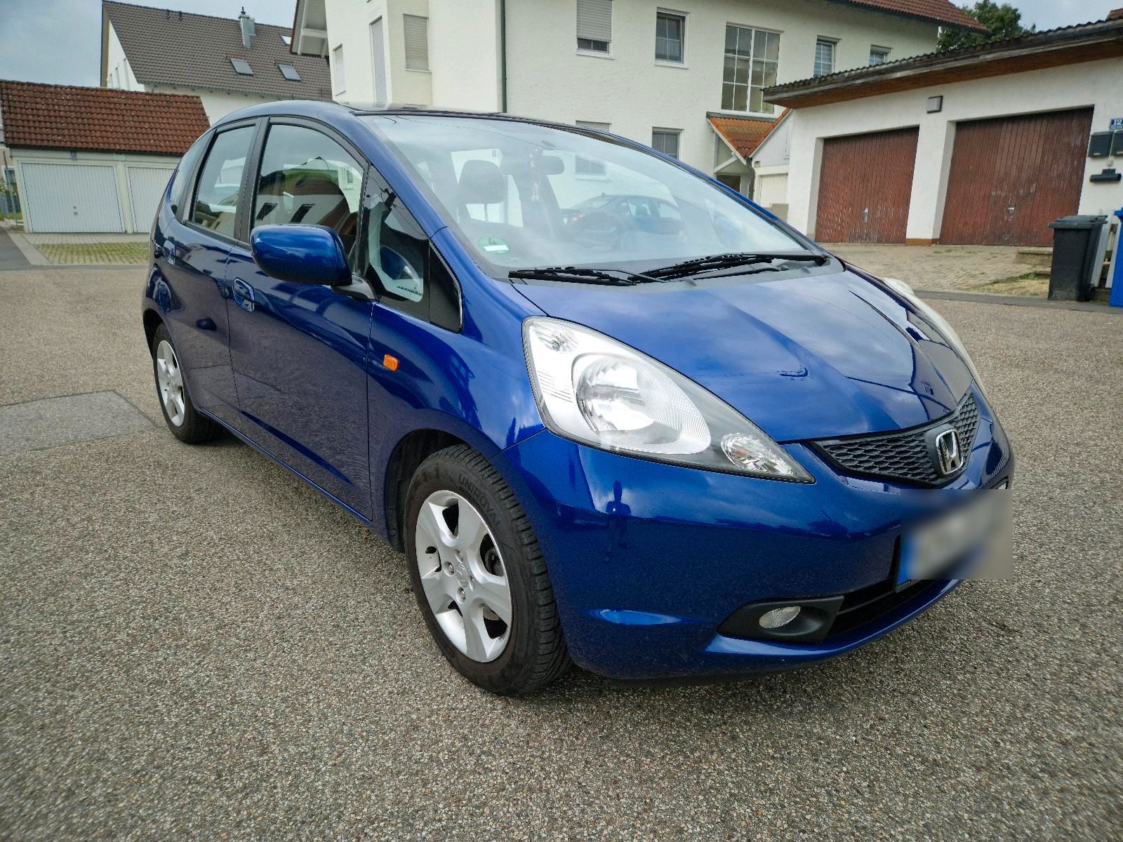 A used Honda Jazz in blue is parked in the courtyard.