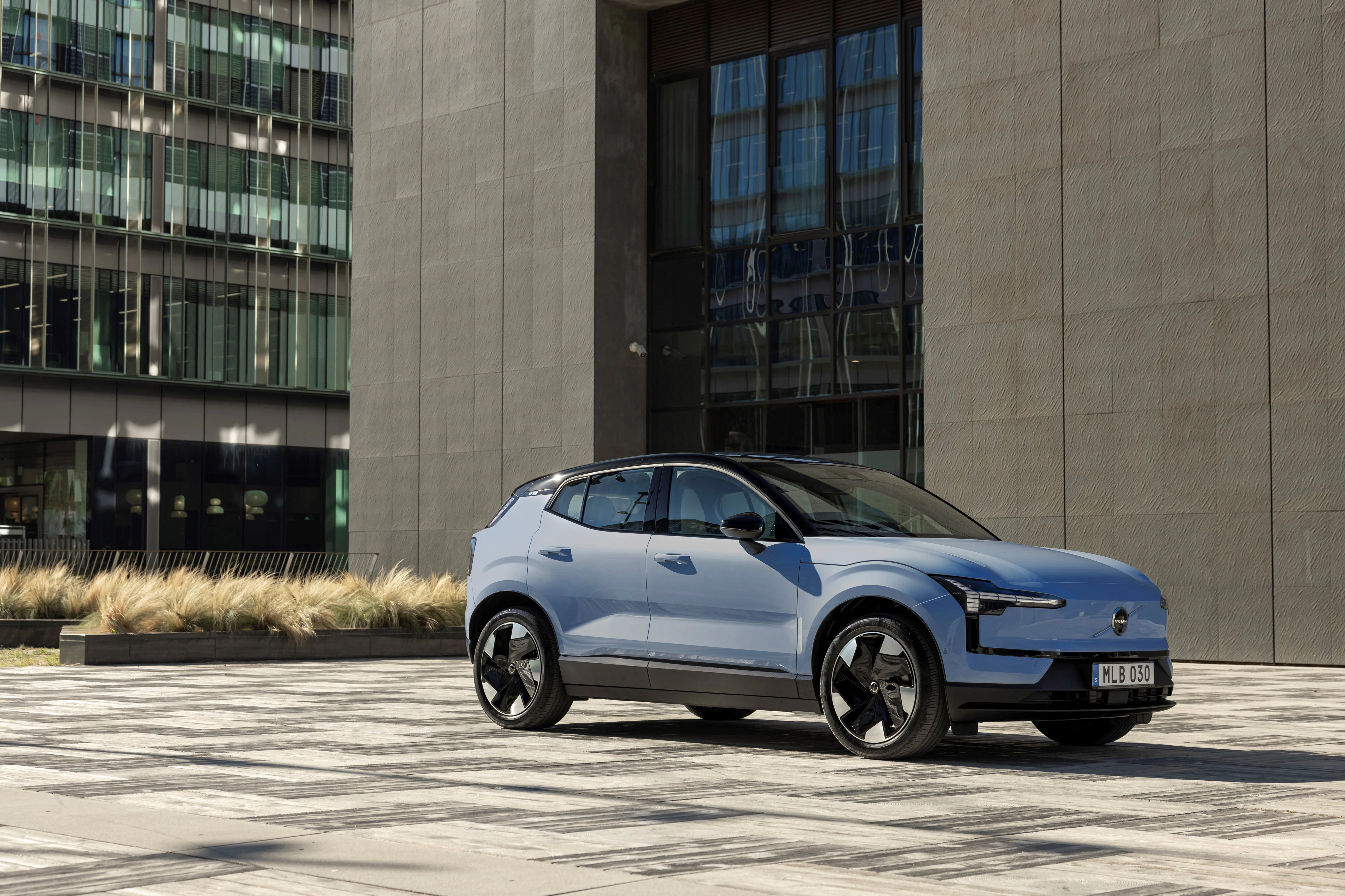 Ein blauer Volvo EX30 steht vor einem urbanen Gebäude