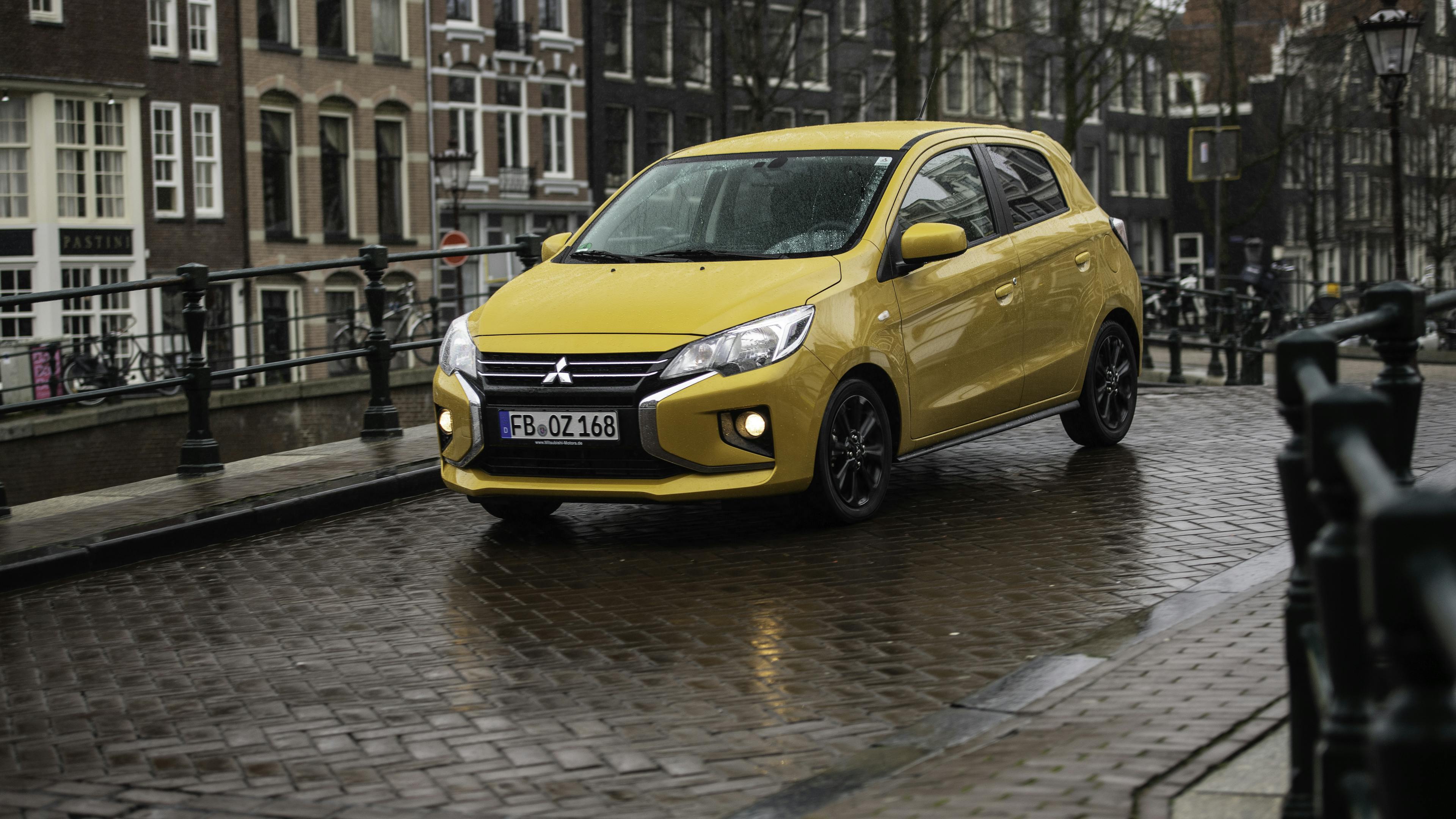 A yellow Mitsubishi Space Star, photographed from diagonally in front on a bridge in the Netherlands.