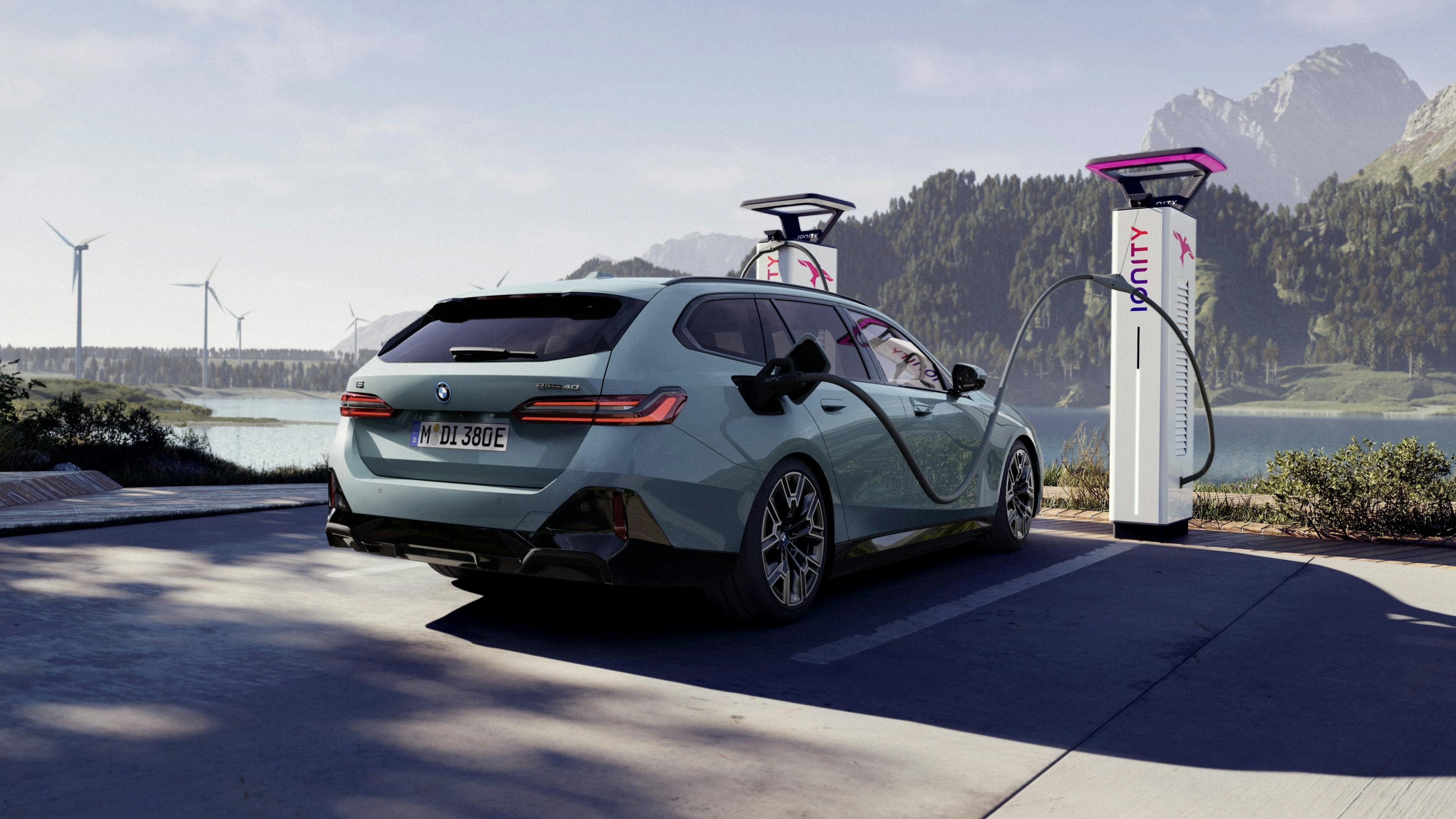 A BMW i5 Touring is charged at a charging station.