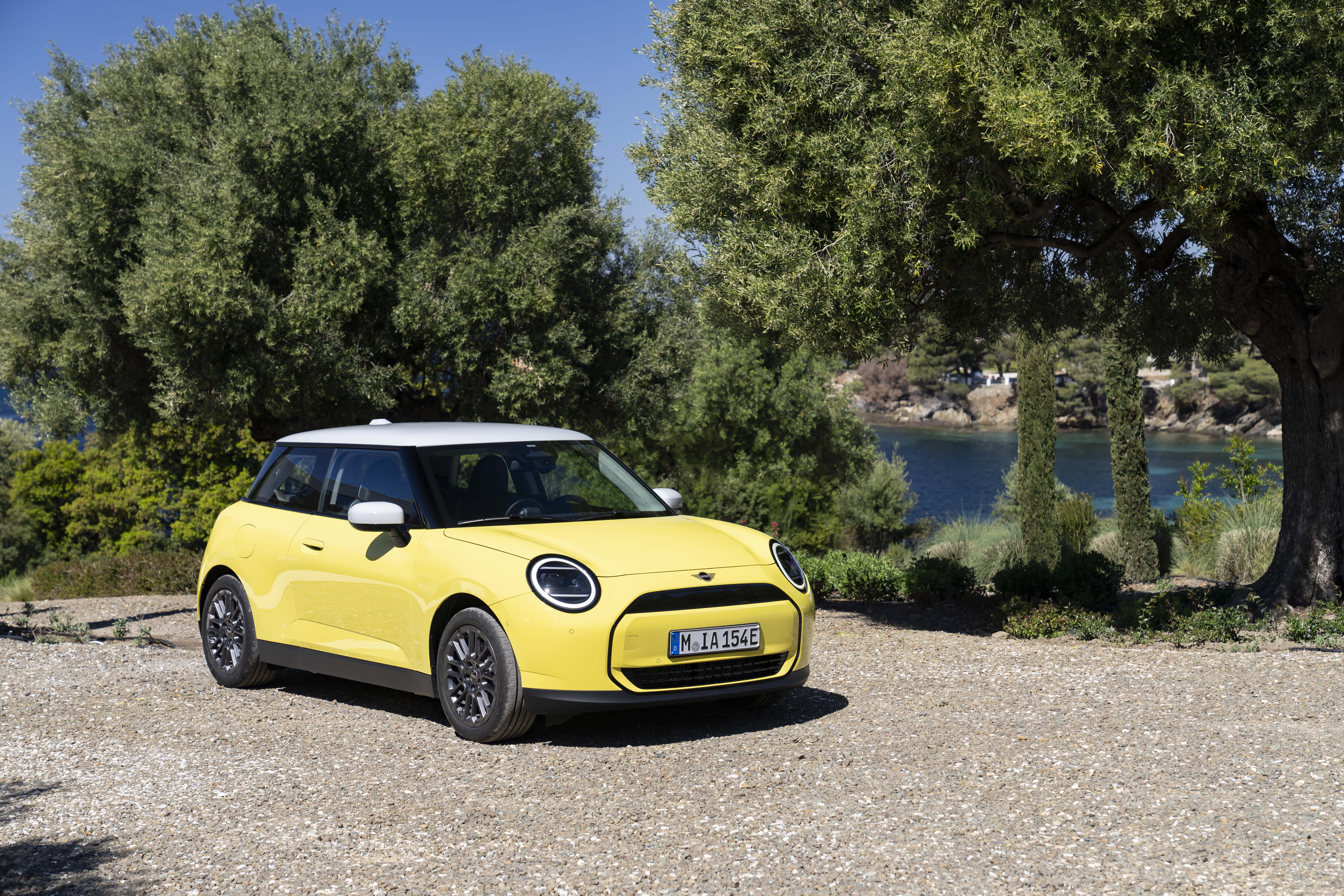 Ein gelber Mini Cooper Electric parkt auf Schotter