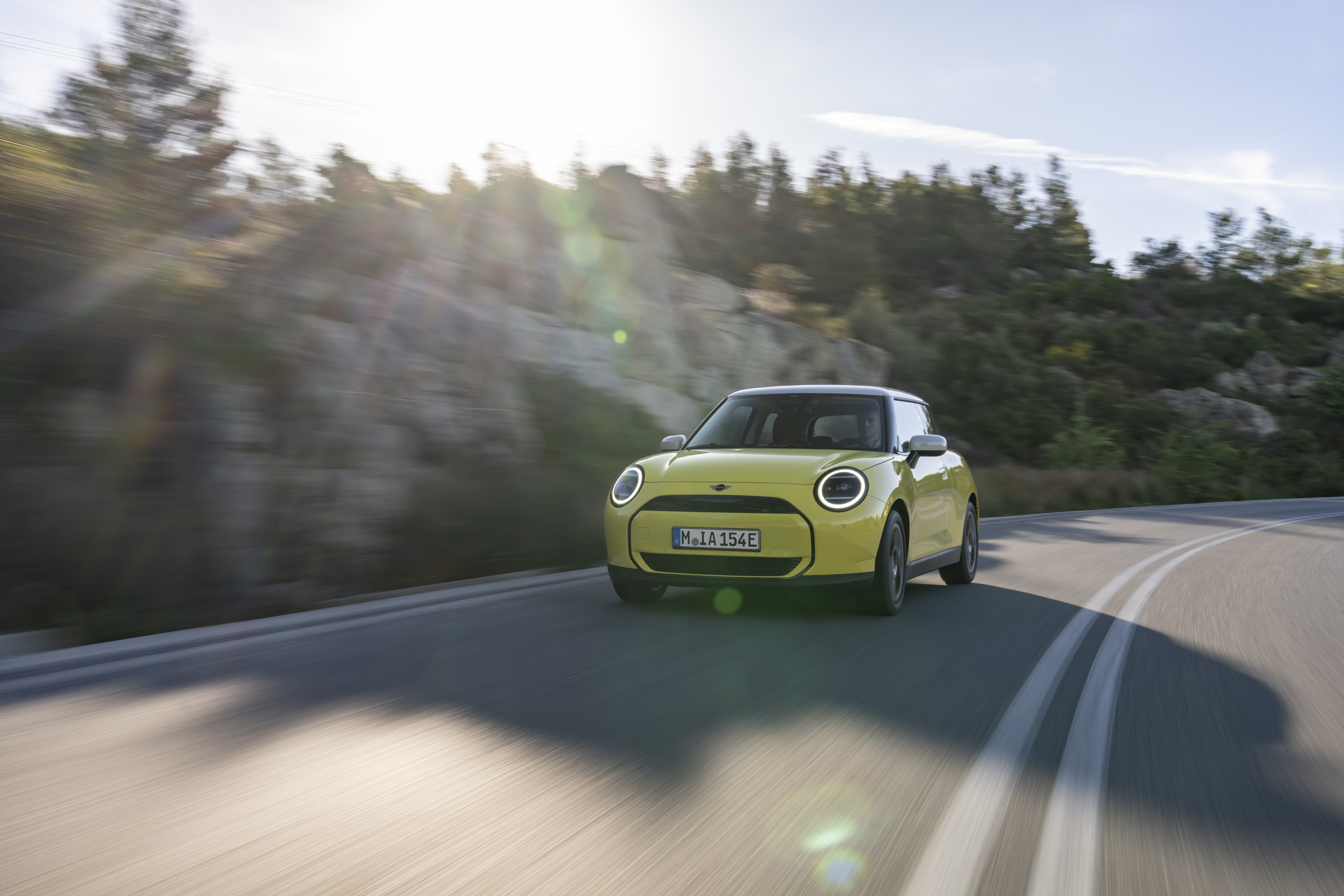 Ein gelber Mini Cooper Electric fährt auf der Landstraße