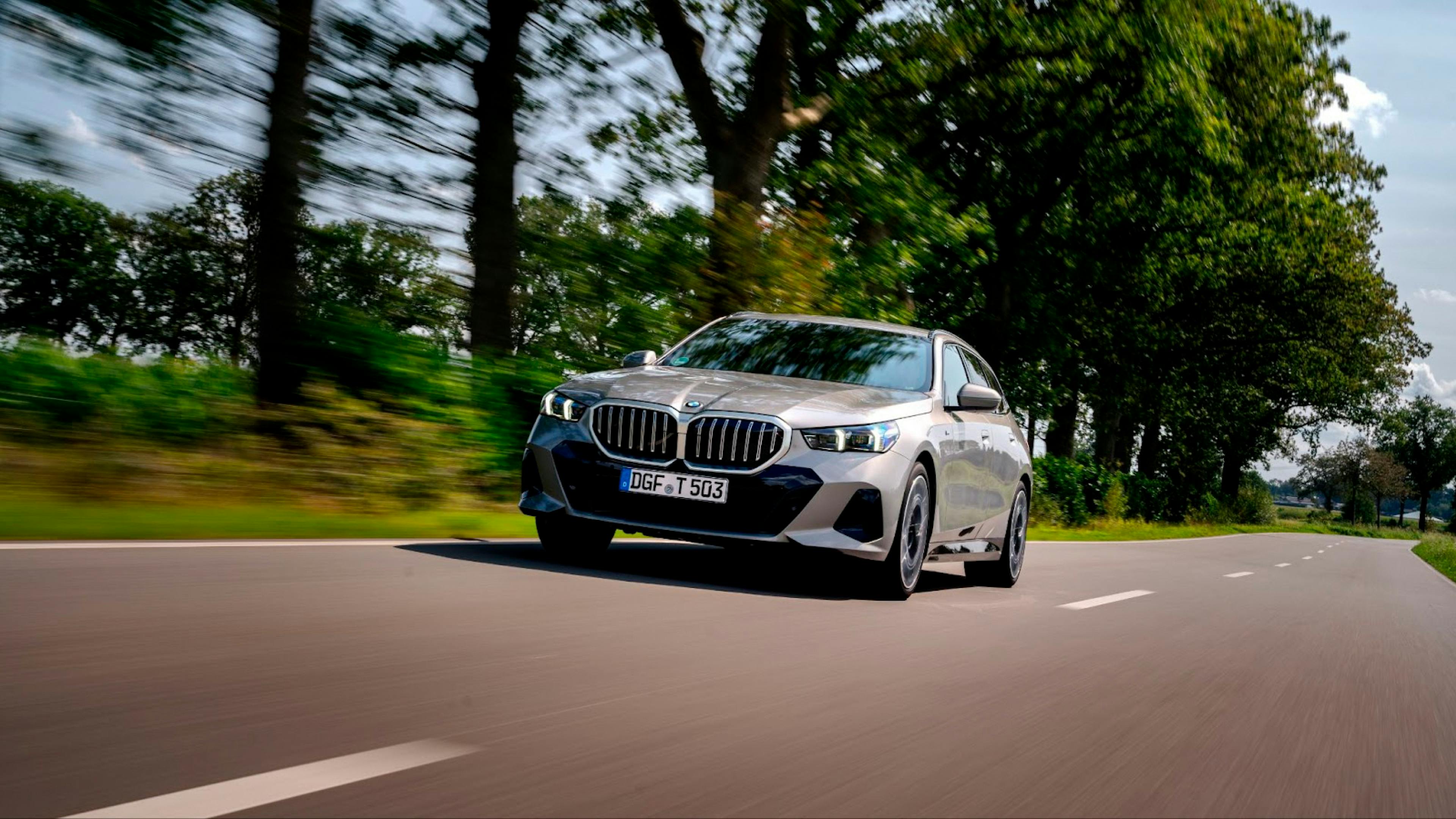 Silver BMW 5 Series Touring, driving on a country road.
