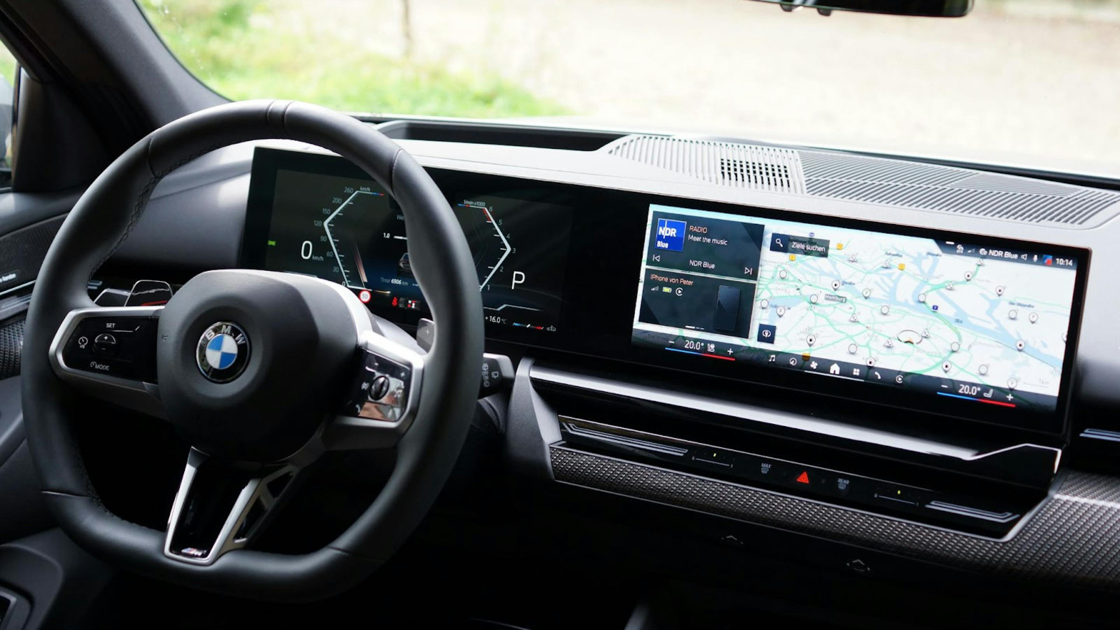 Steering wheel with BMW logo, the digital instruments behind it and the large touchscreen next to it.