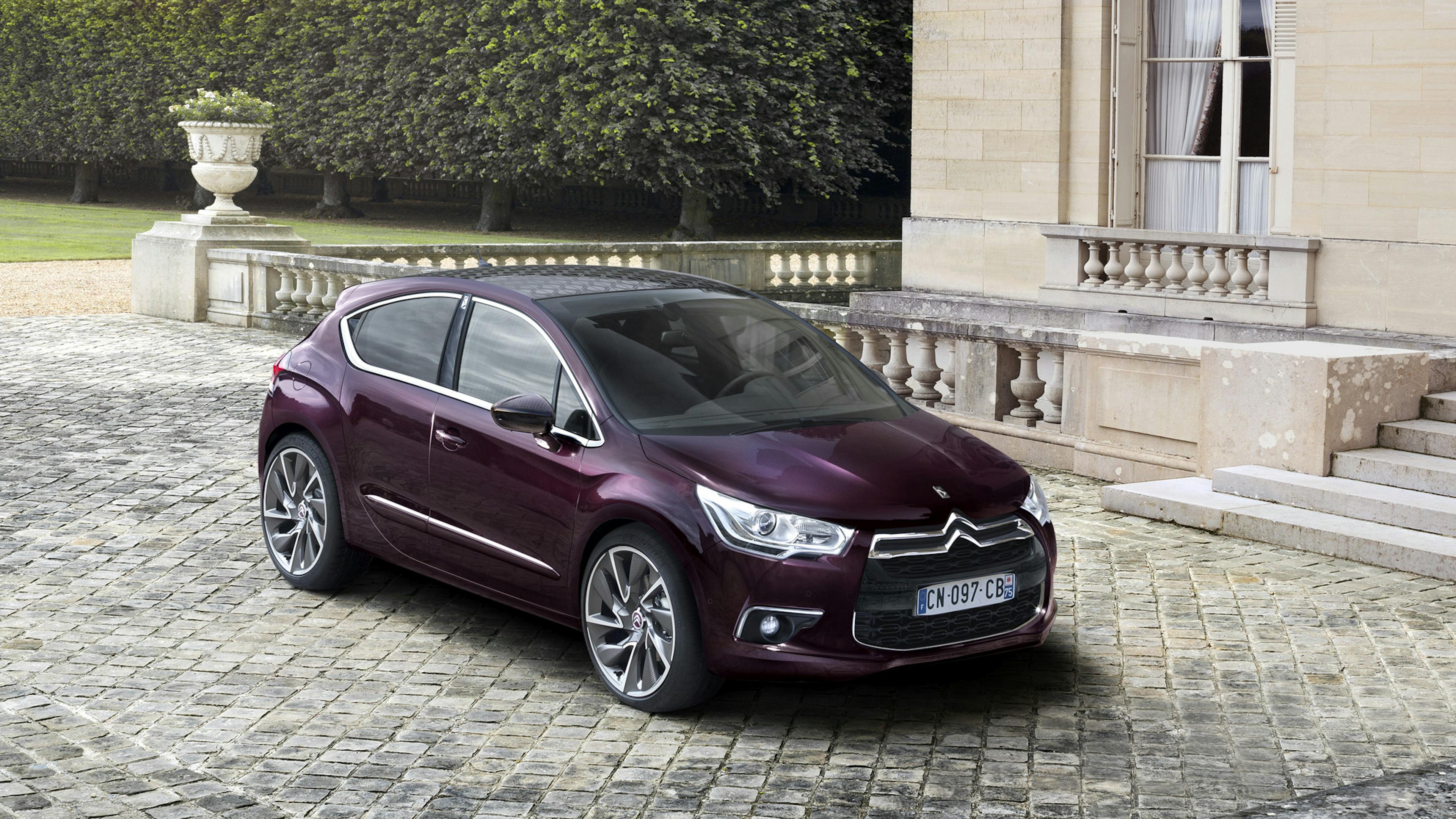 A DS 4 is parked in front of a French country estate.