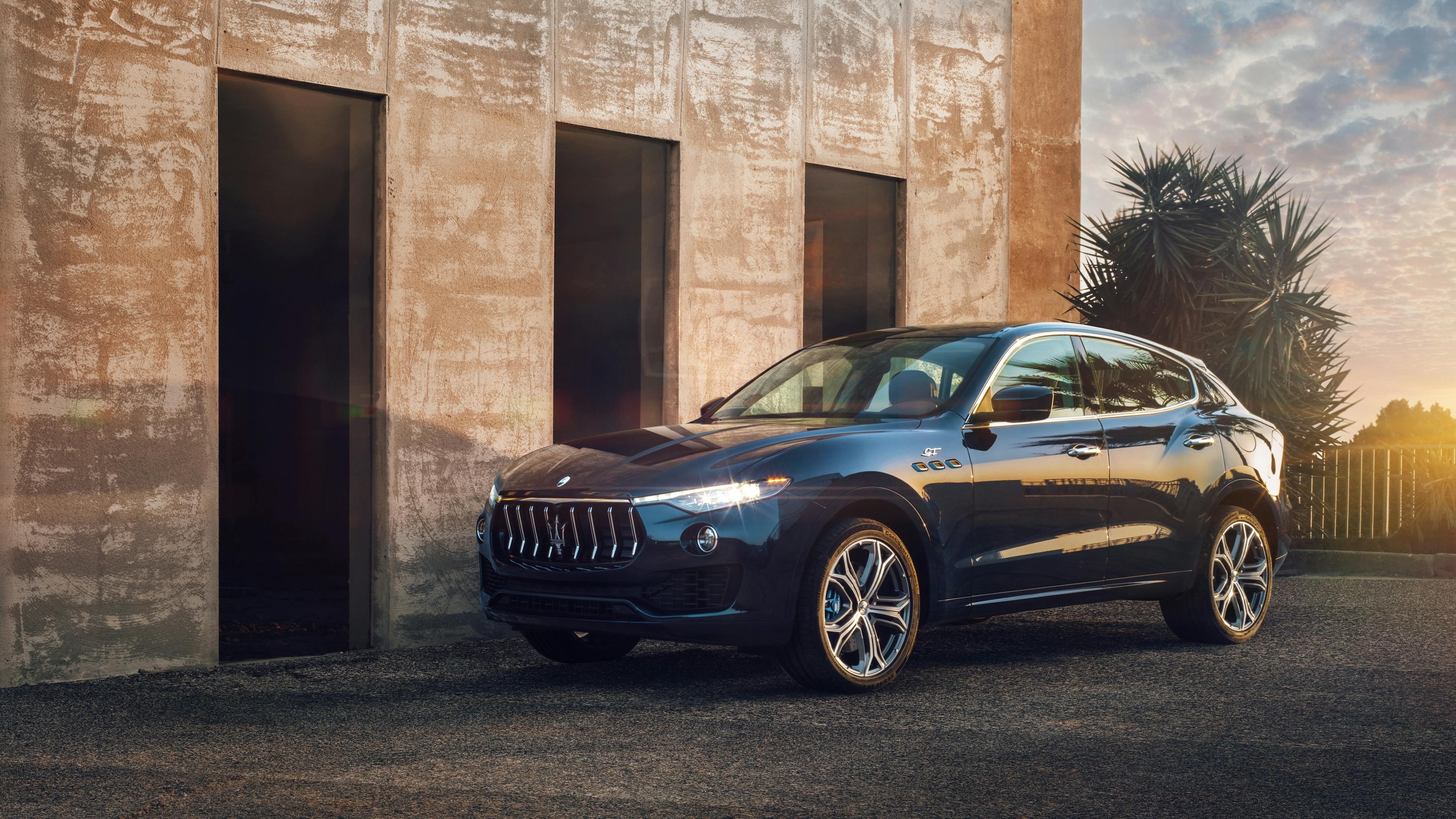 A black Maserati Levante stands in front of a modern exposed concrete building.