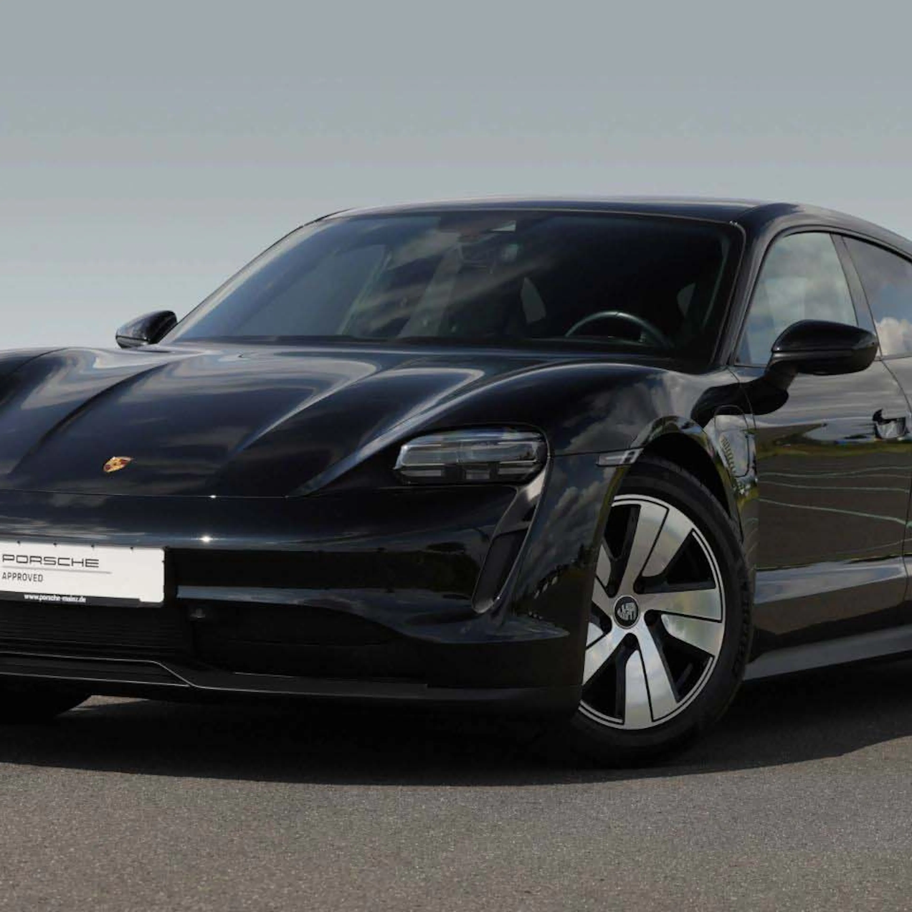 Ein schwarzer Porsche Taycan Sport Turismo steht im Verkaufsraum eines Händlers.