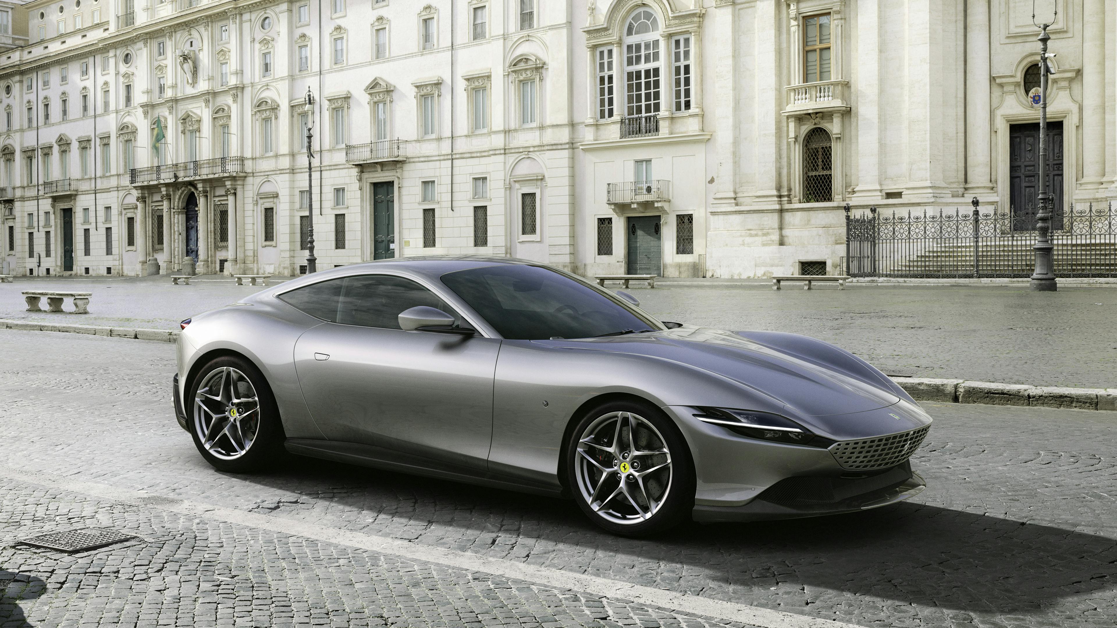 A silver Ferrari Roma stands in front of historic buildings.