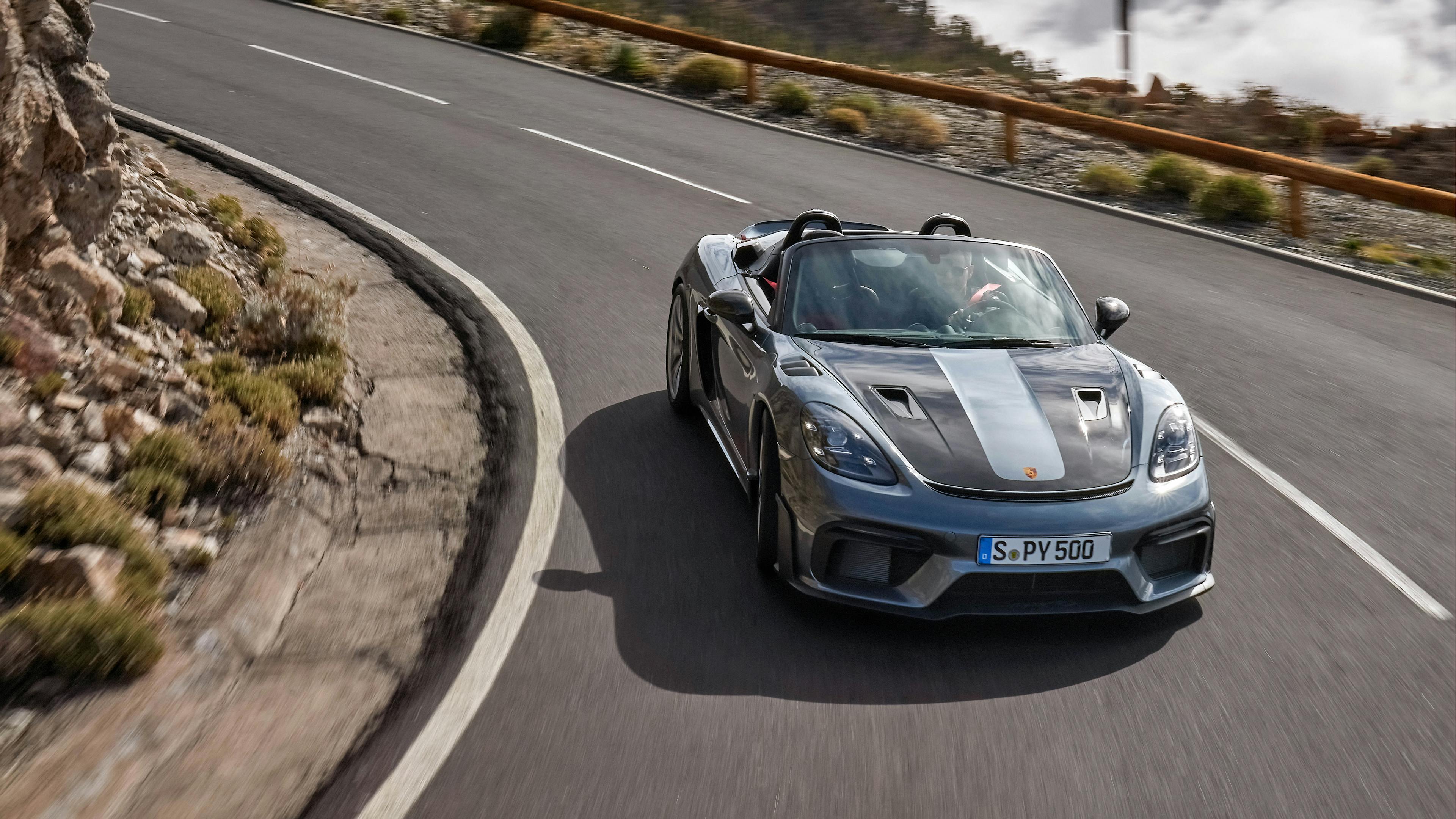 A Porsche 718 Spyder RS drives through a curve on a mountain road.