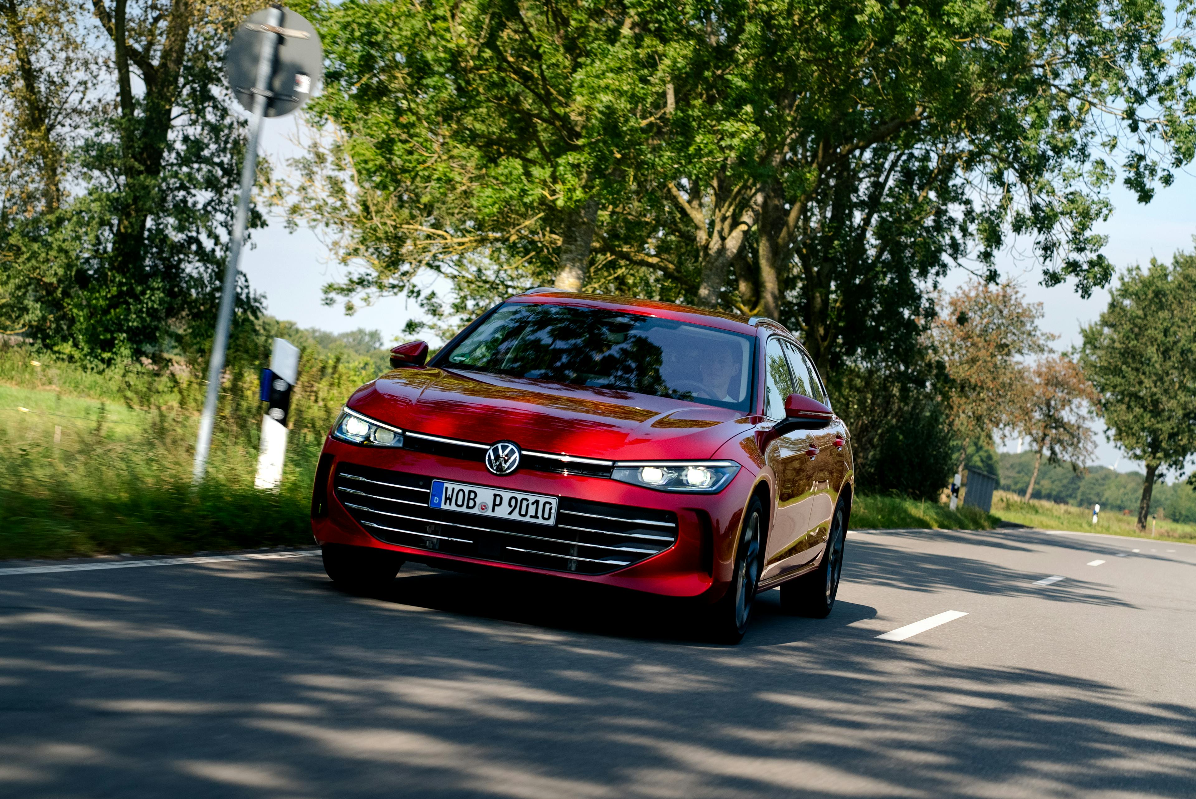 Ein roter VW Passat B9, fahrend auf einer Landstraße.