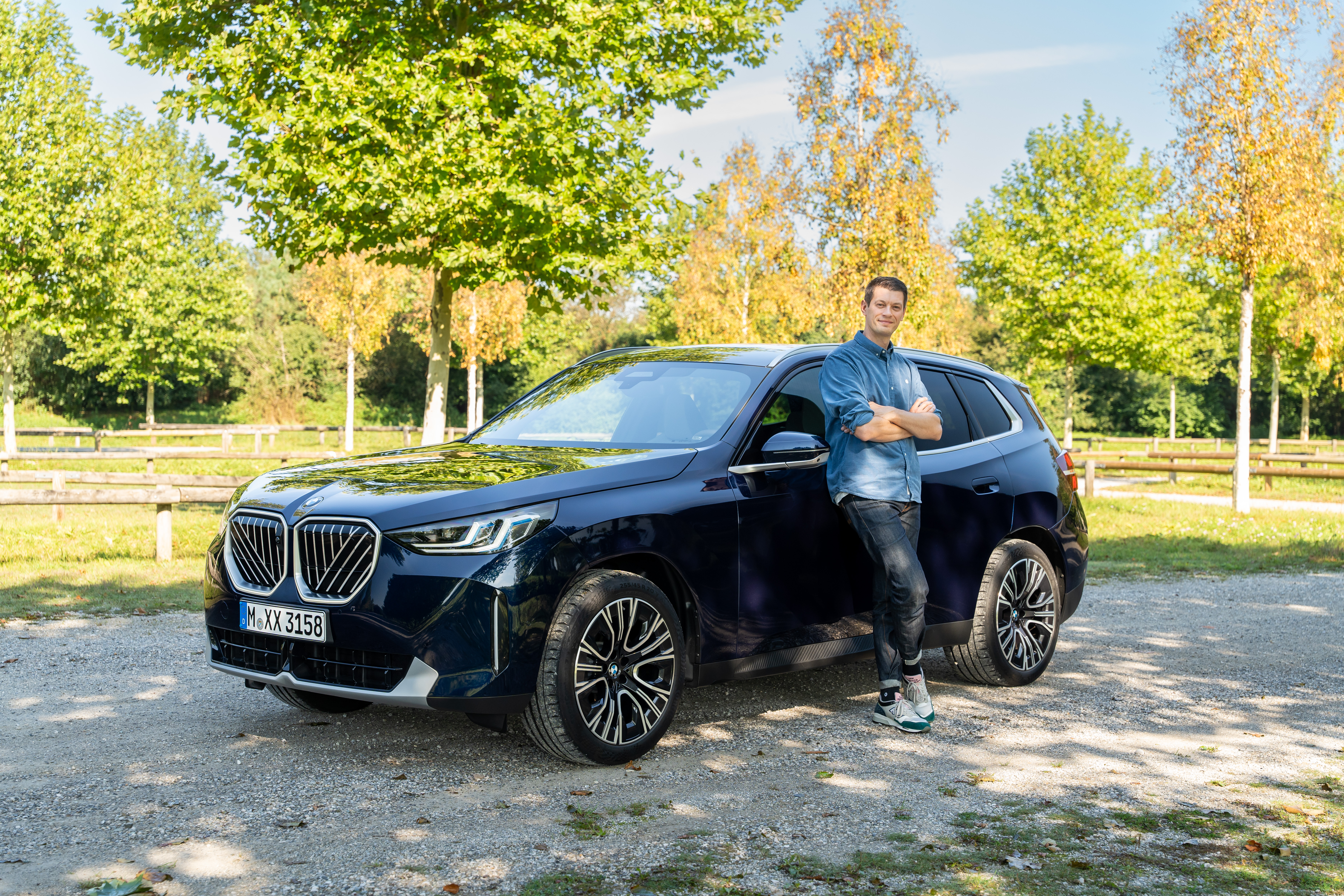 Ein blauer BMW X3 G45 auf einem Parkplatz mit dem Redakteur am Auto stehend.
