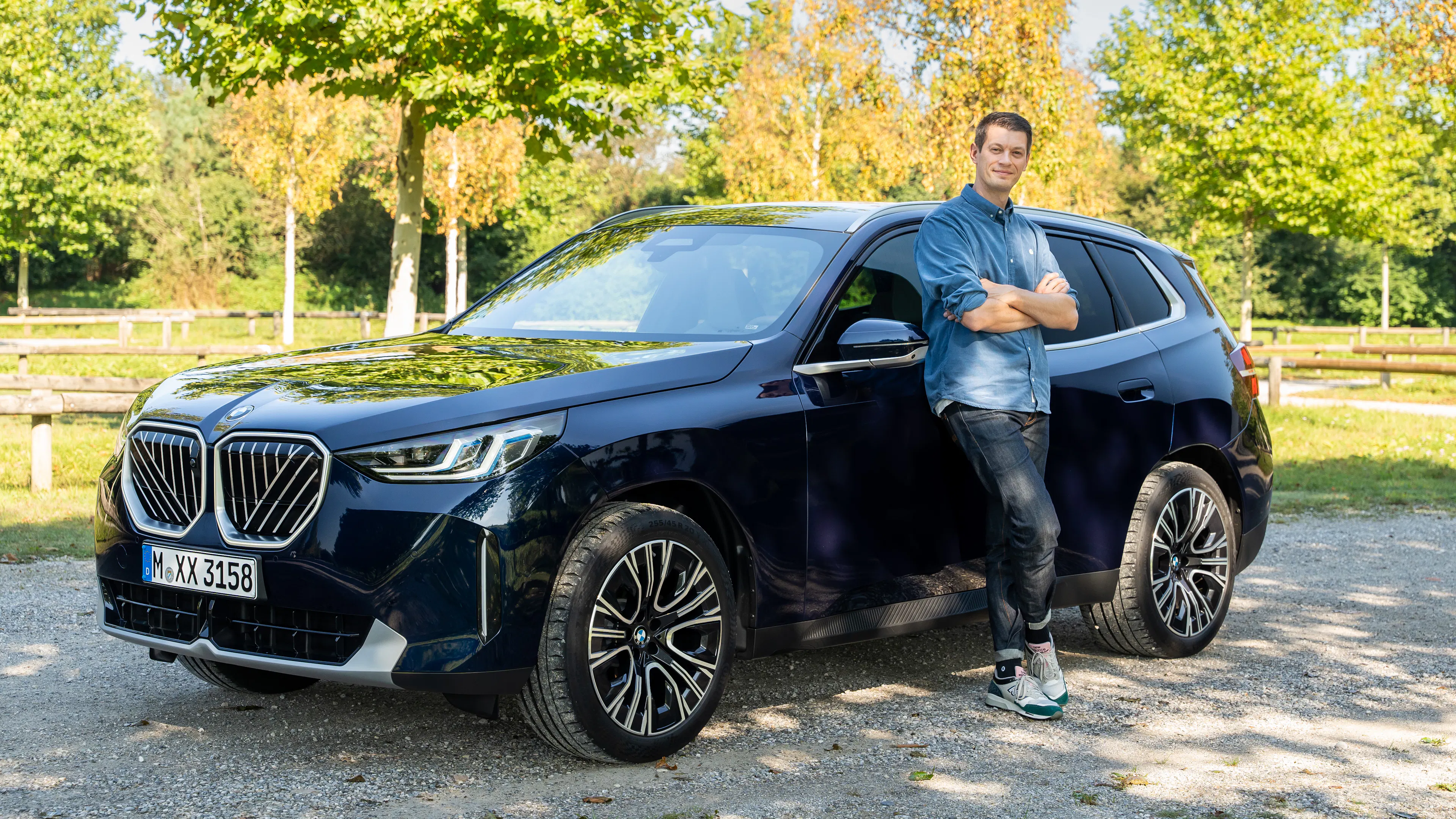 Ein blauer BMW X3 G45 auf einem Parkplatz mit dem Redakteur am Auto stehend.