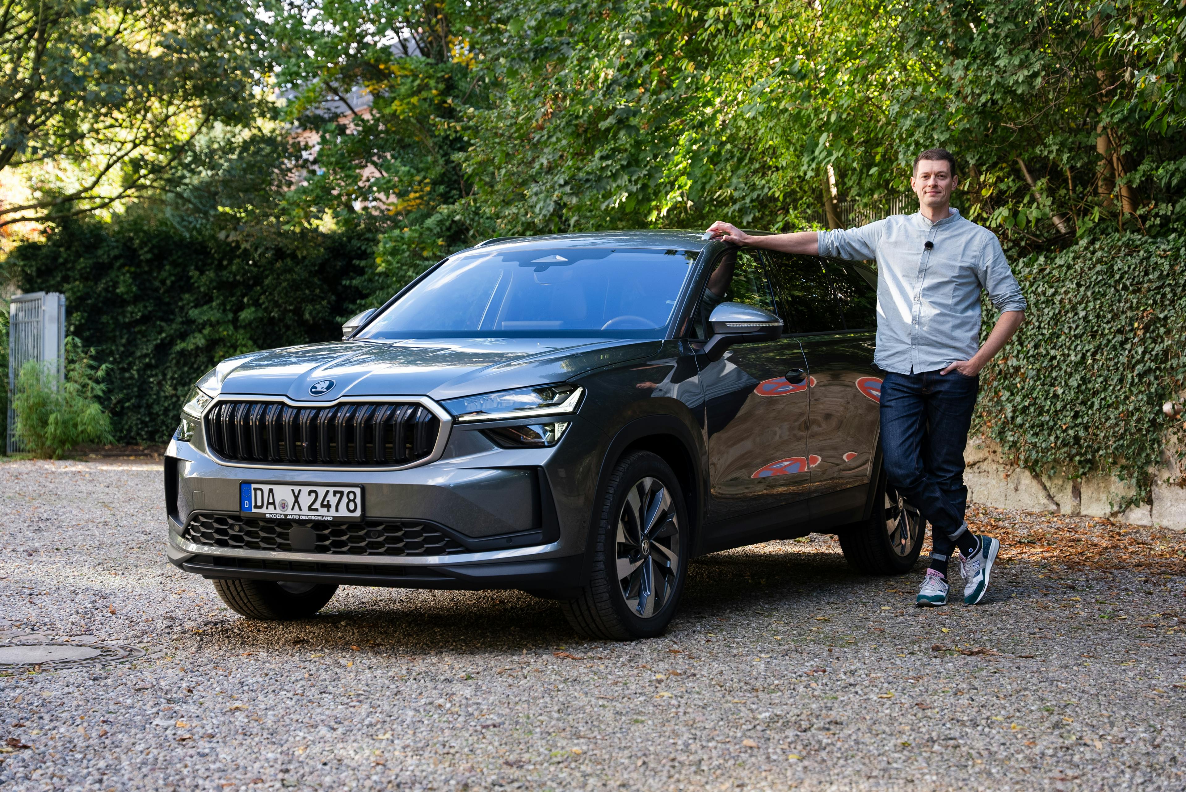 Ein grausilberner Škoda Kodiaq auf einem Parkplatz mit dem Redakteur, am Auto stehend