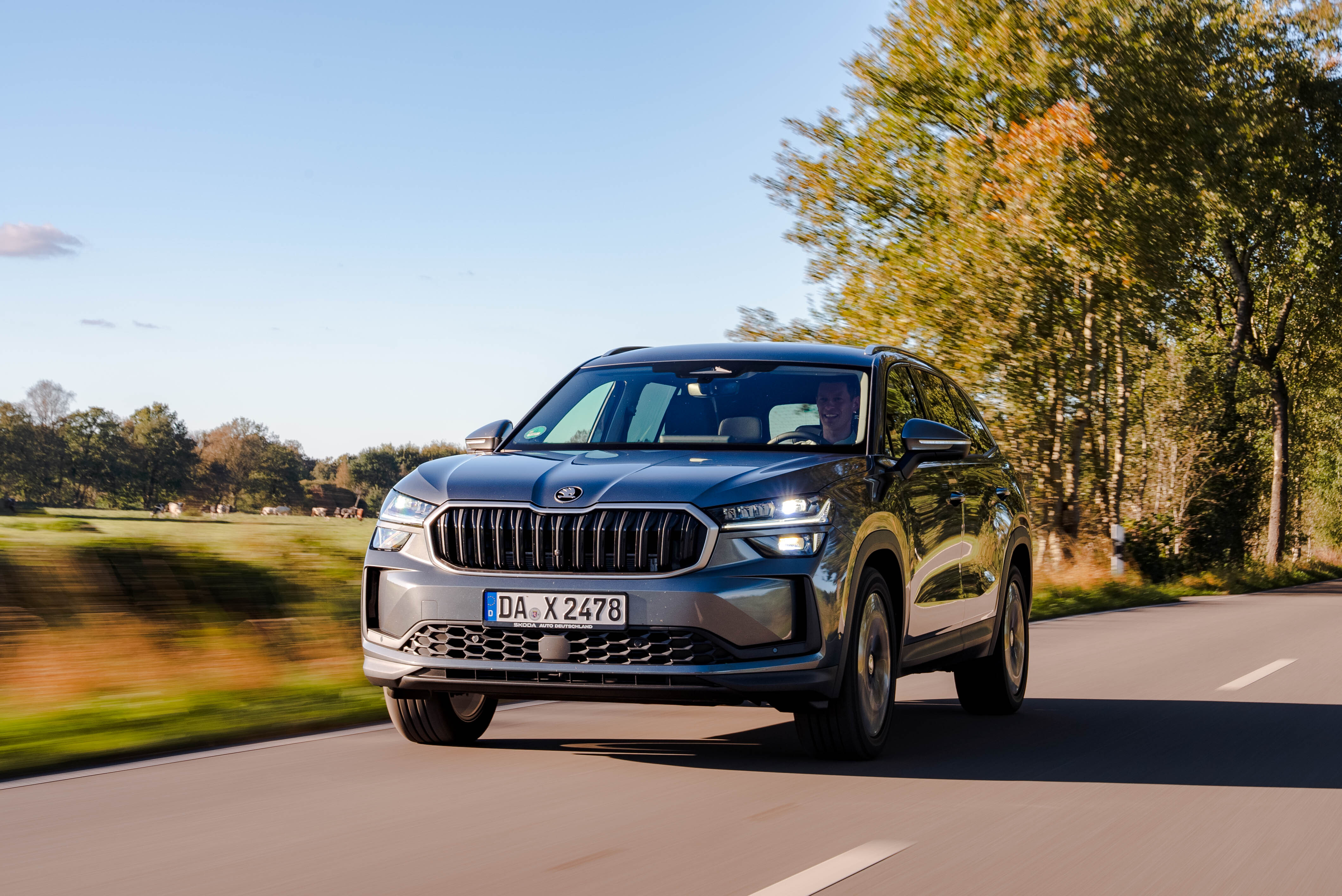 Gray Škoda Kodiaq, driving on an autumnal country road.