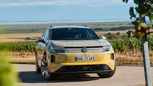 VW ID.Tiguan mit Tarnfolie steht vor Weinbergen, Frontansicht.