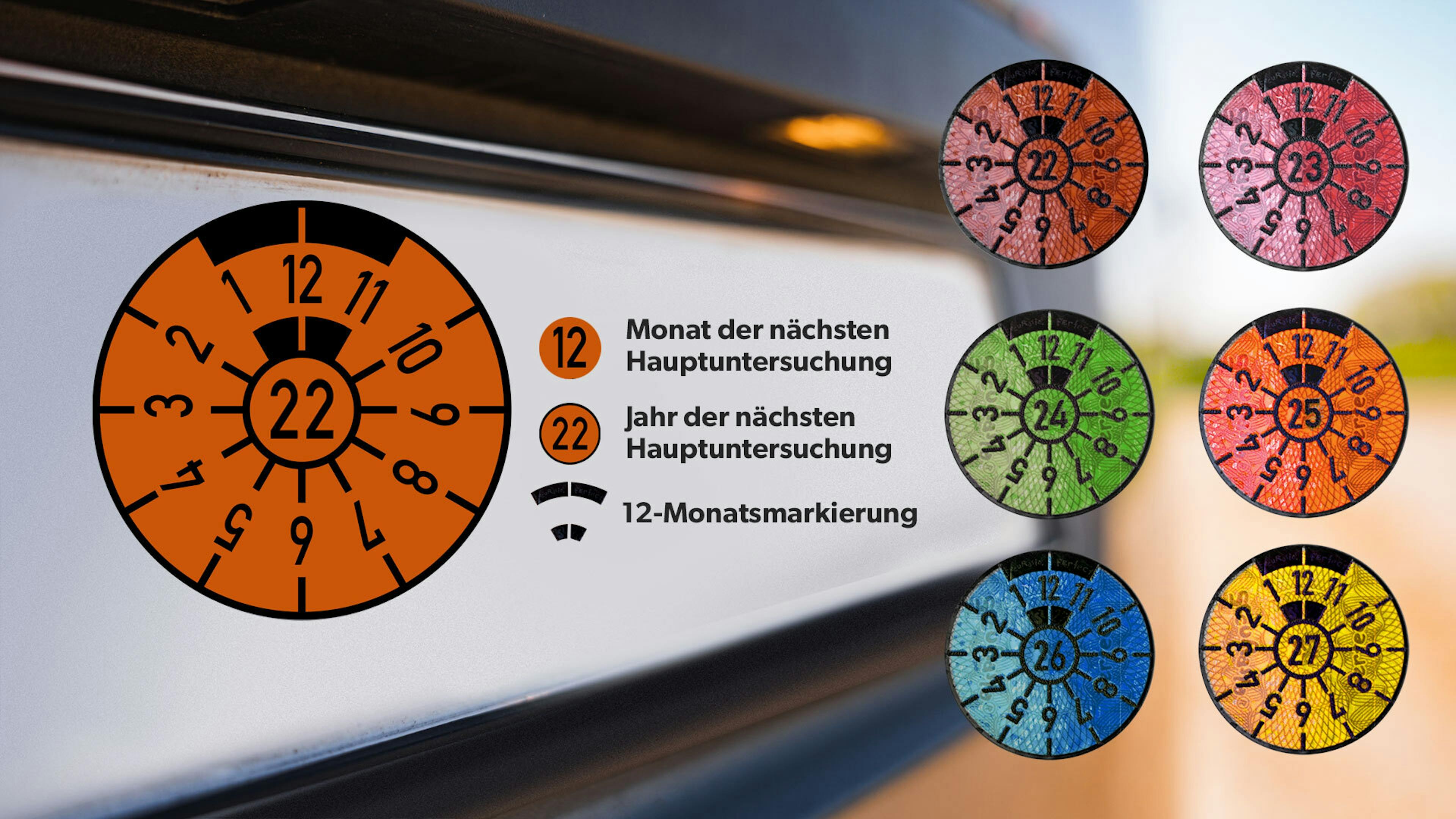 TÜV-Plaketten werden nach Farben sortiert auf einem verschwommenen Nummernschild dargestellt.