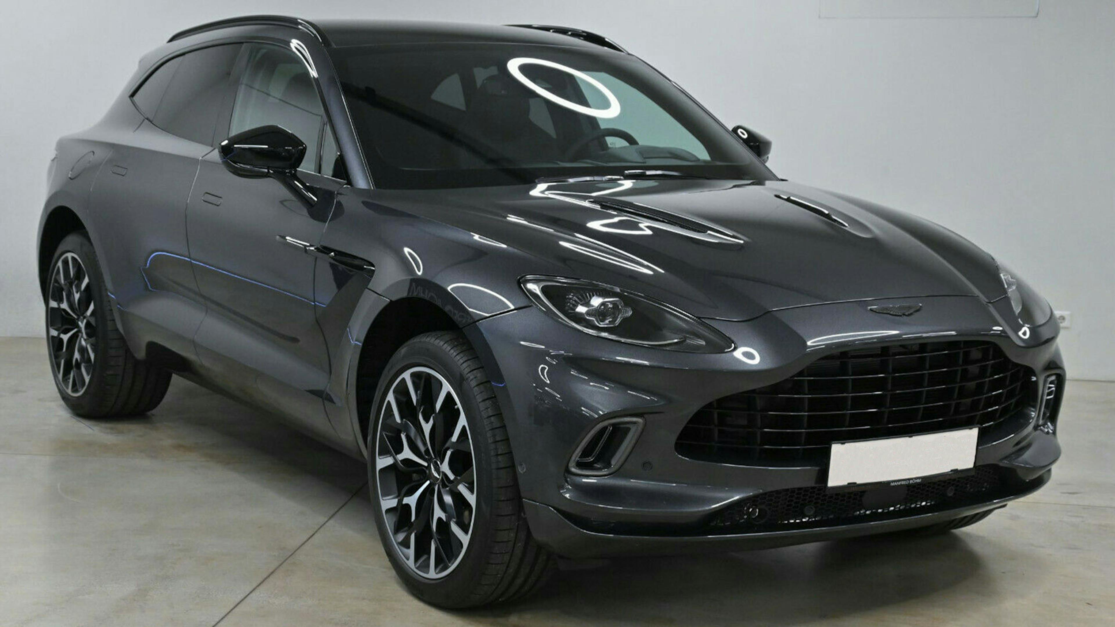Ein schwarzer Aston Martin steht in einem Raum mit weißen Wänden.