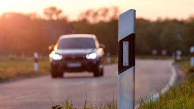 Ein Pkw fährt im Abendlicht eine Straße entlang