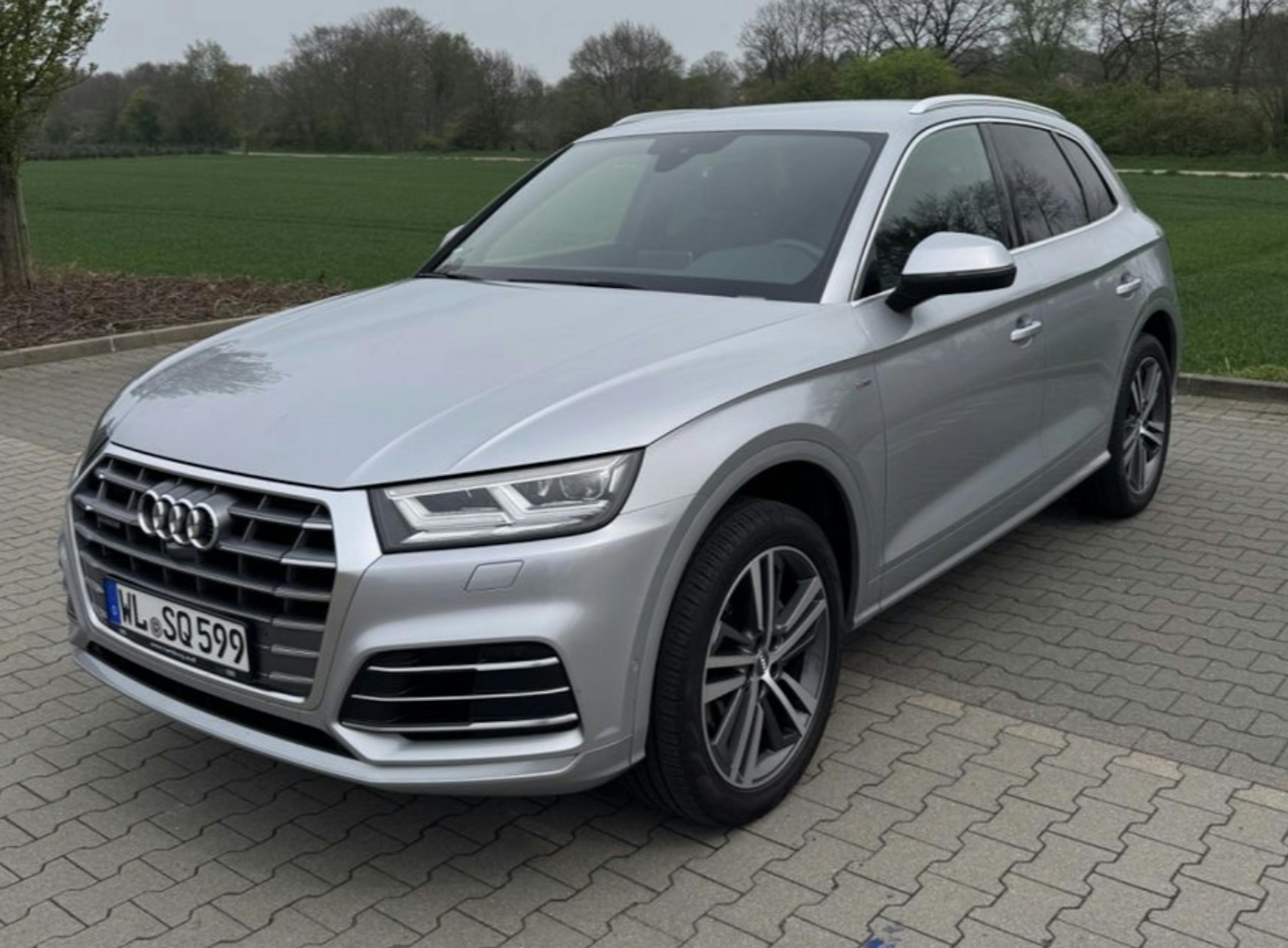 Ein hellgrauer Audi Q5 parkt auf Pflastersteinen