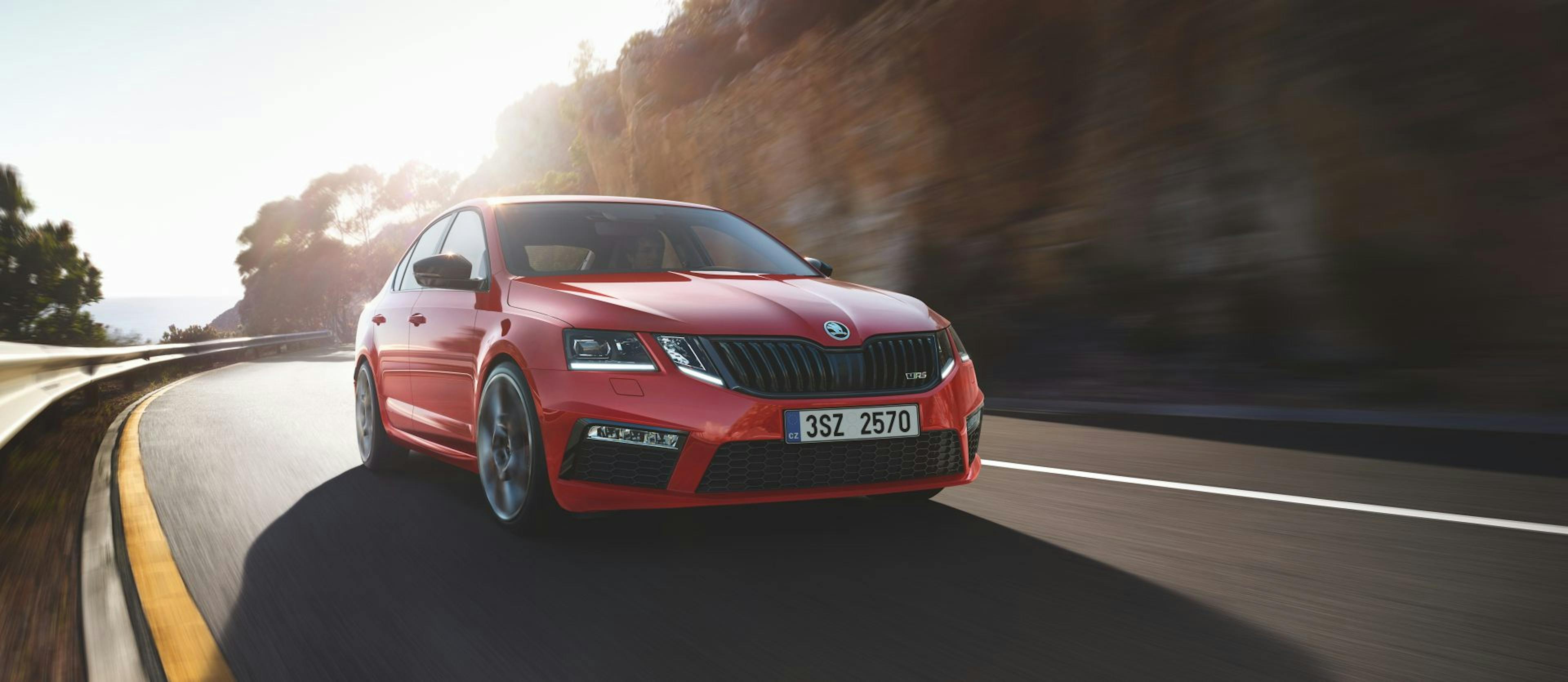 Ein roter Škoda Octavia fahrend auf einer Landstraße.