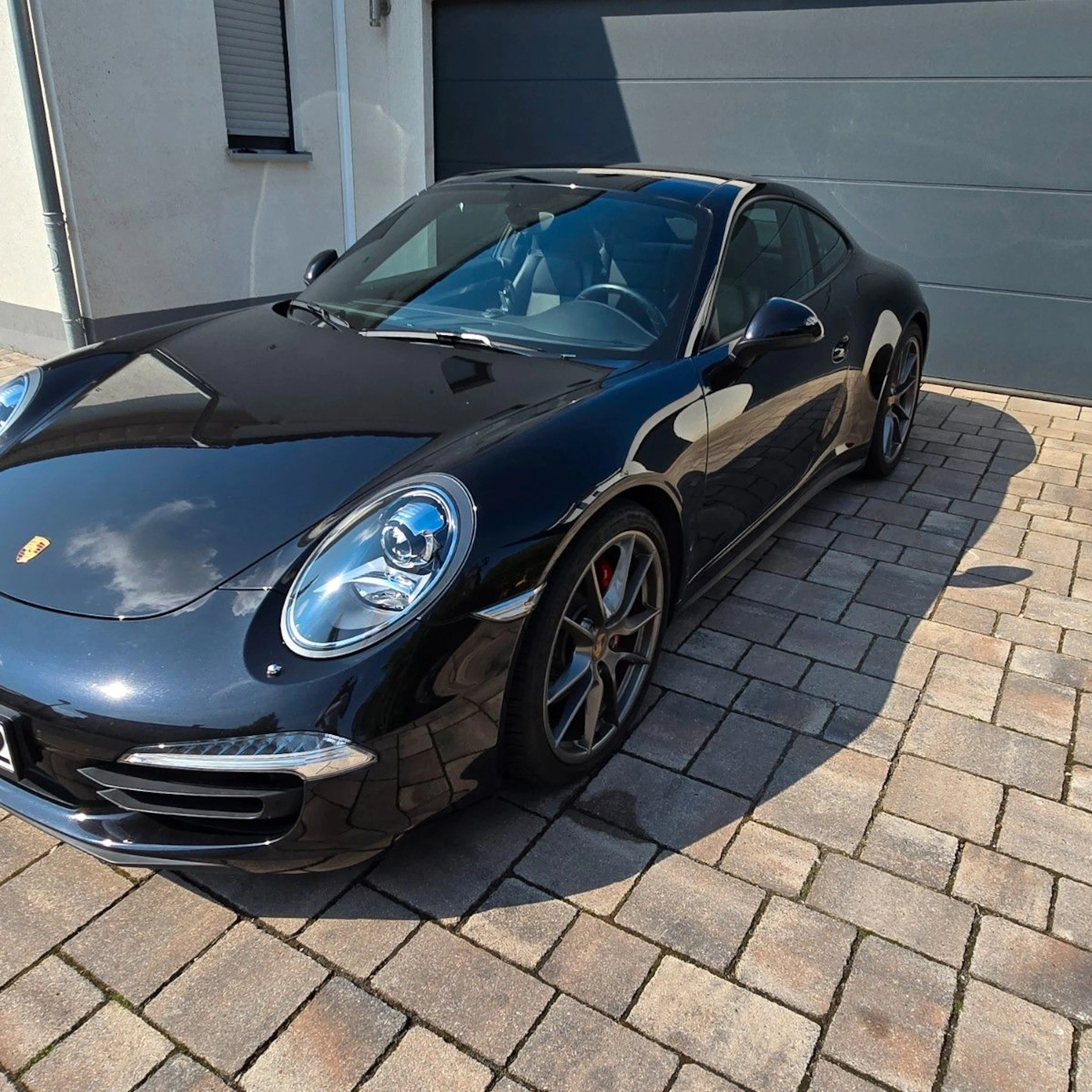 Ein schwarzer Porsche 911 Cabrio steht vor einer Garage.