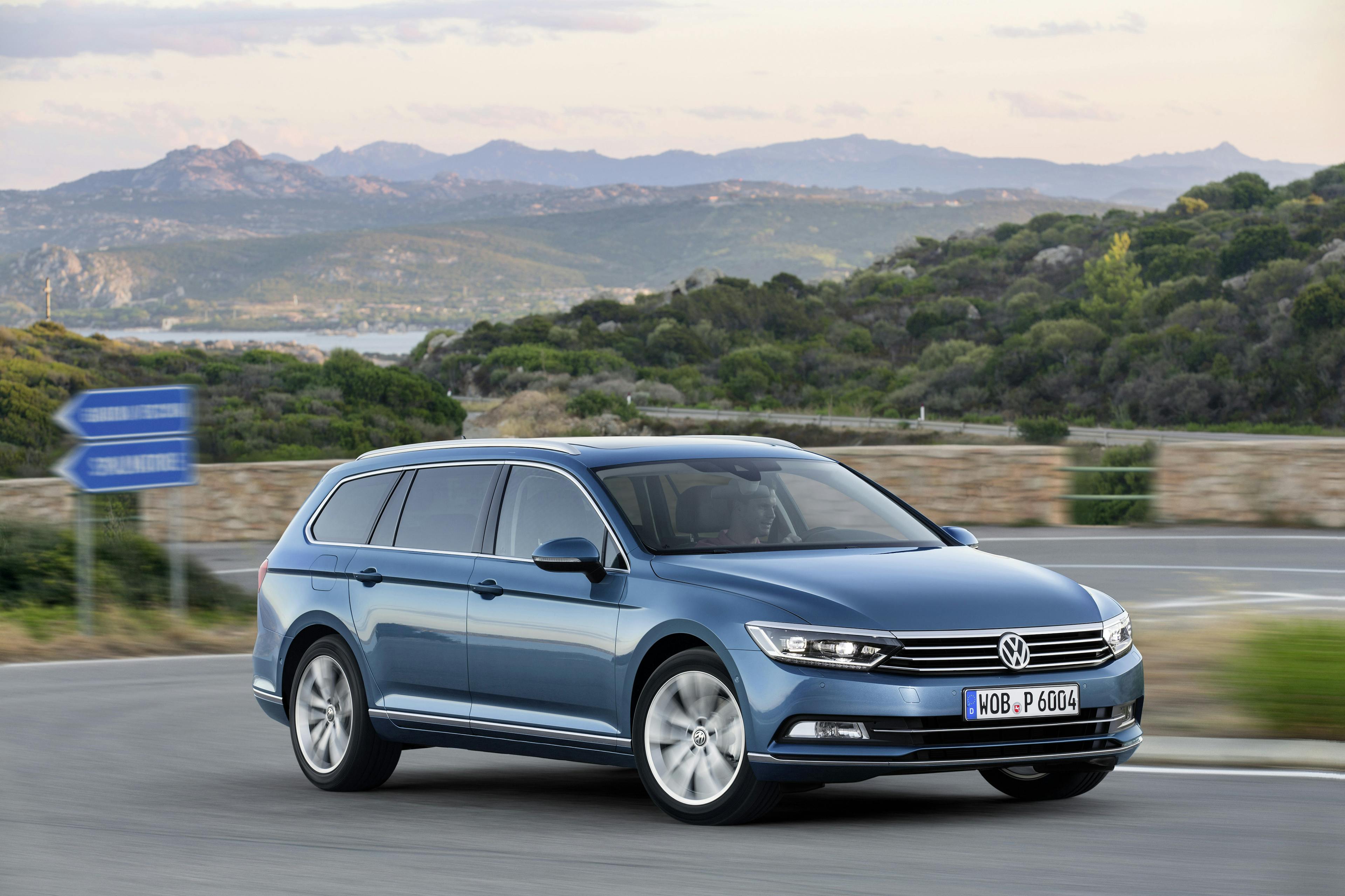 Ein blauer VW Passat Variant fährt eine Bergstraße hinauf.