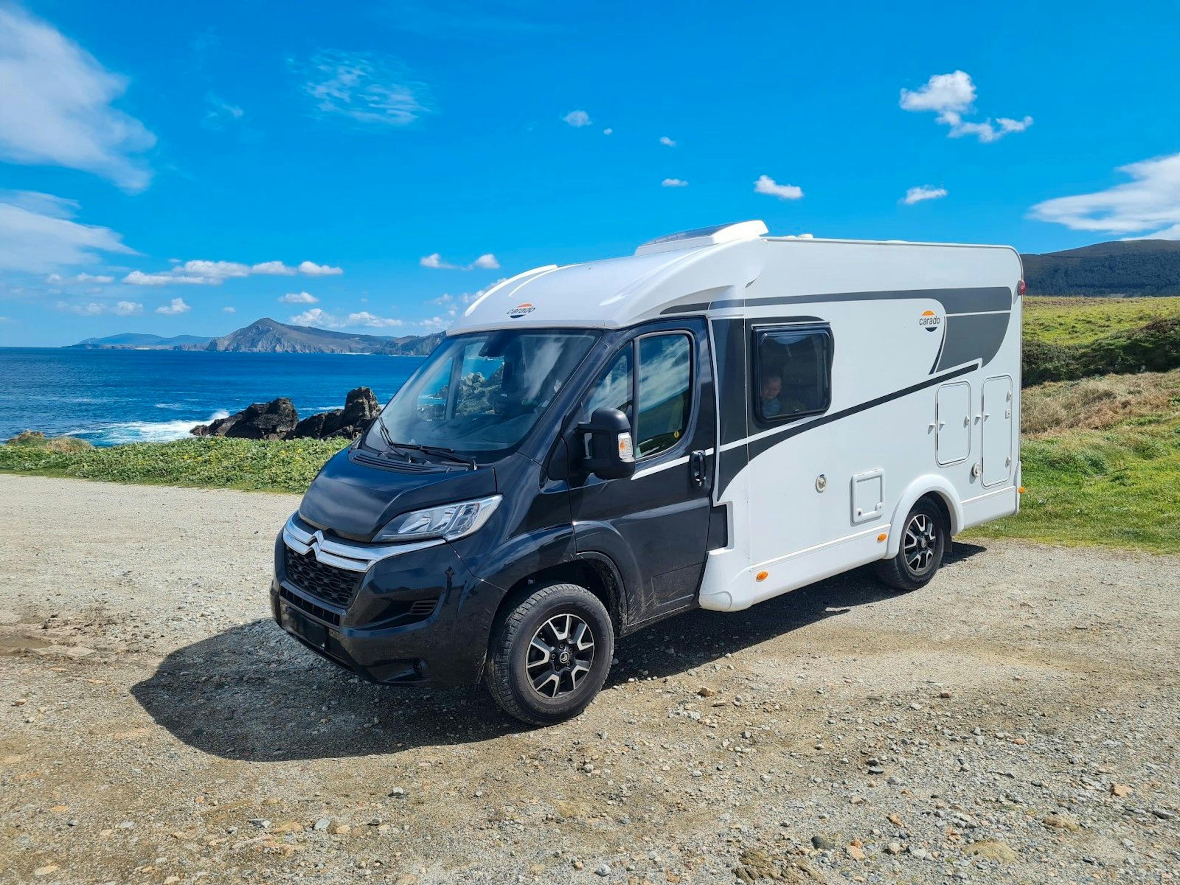 Teilintegriertes Wohnmobil von Carado auf Citroën-Basis, abgestellt vor einer Küstenlandschaft mit Blick aufs Meer.