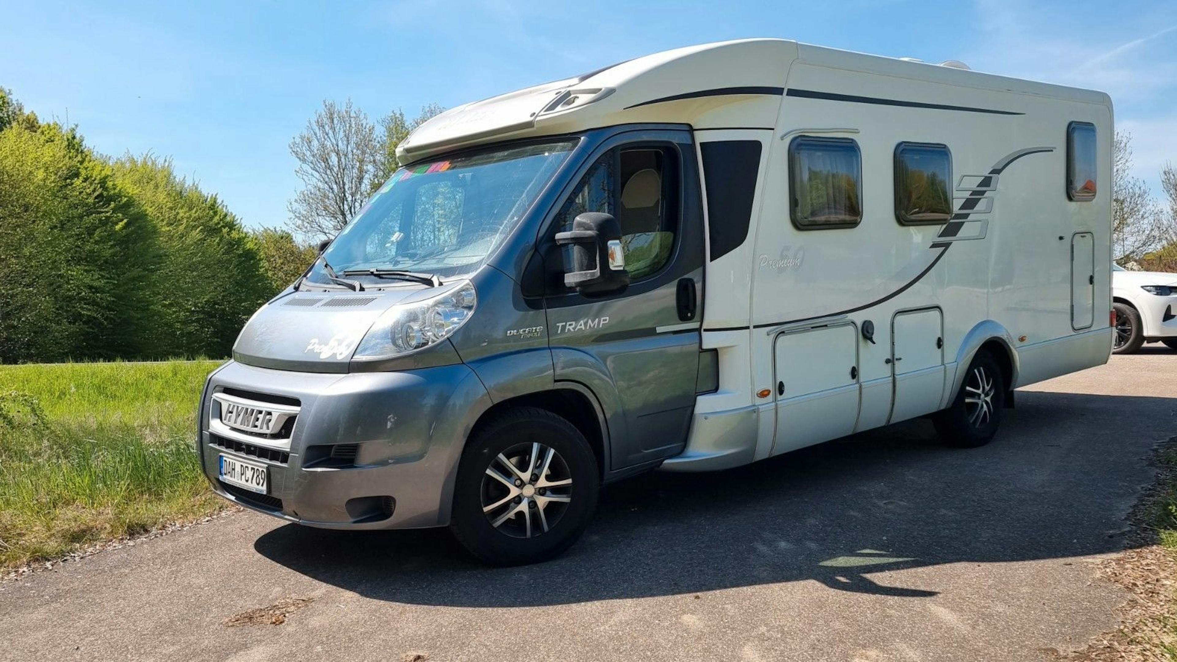 Teilintegriertes Hymer-Wohnmobil der Tramp-Serie auf Fiat Ducato, aufgenommen auf einem ländlichen Parkplatz bei Sonnenschein.