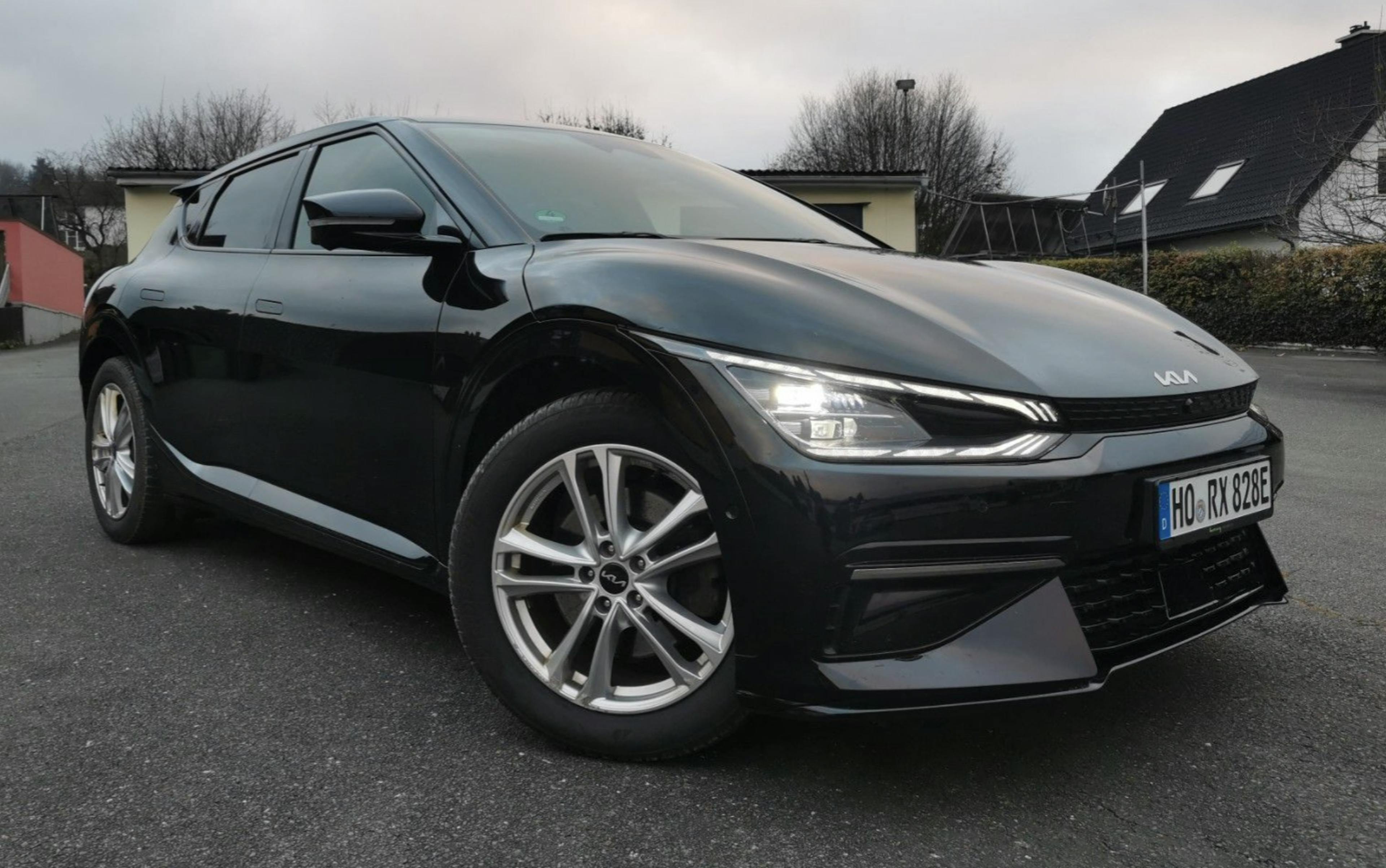 Schwarzer Kia EV6 stehend auf einer Asphaltfläche vor Wohnbebauung.