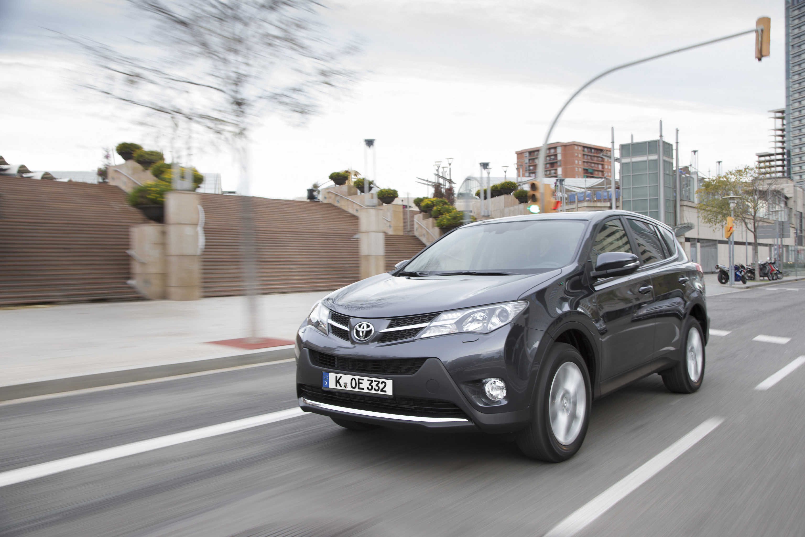 Ein grauer Toyota RAV4 fährt durch eine Innenstadt.