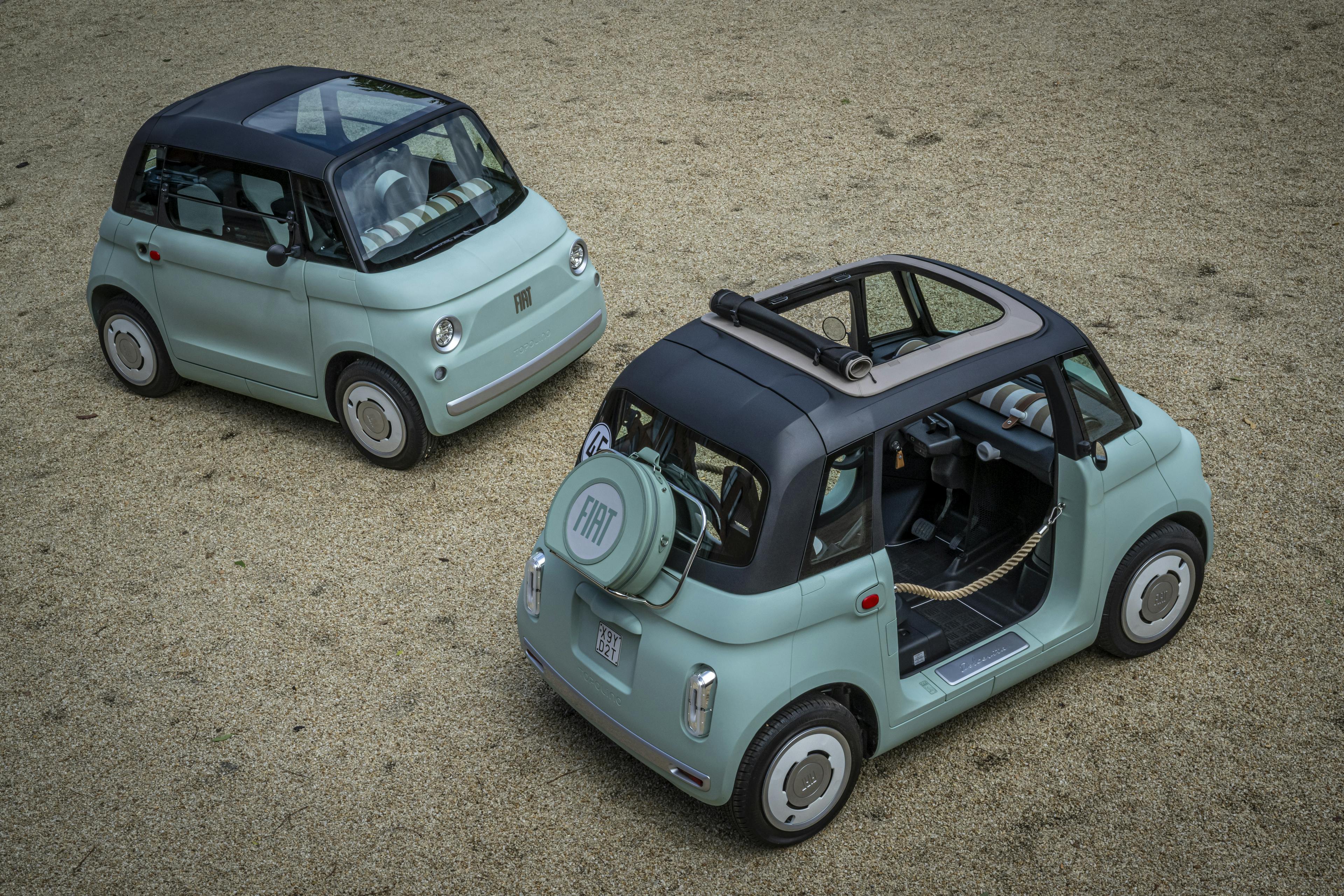 Zwei Fiat Topolino stehen auf einer Kiesfläche.