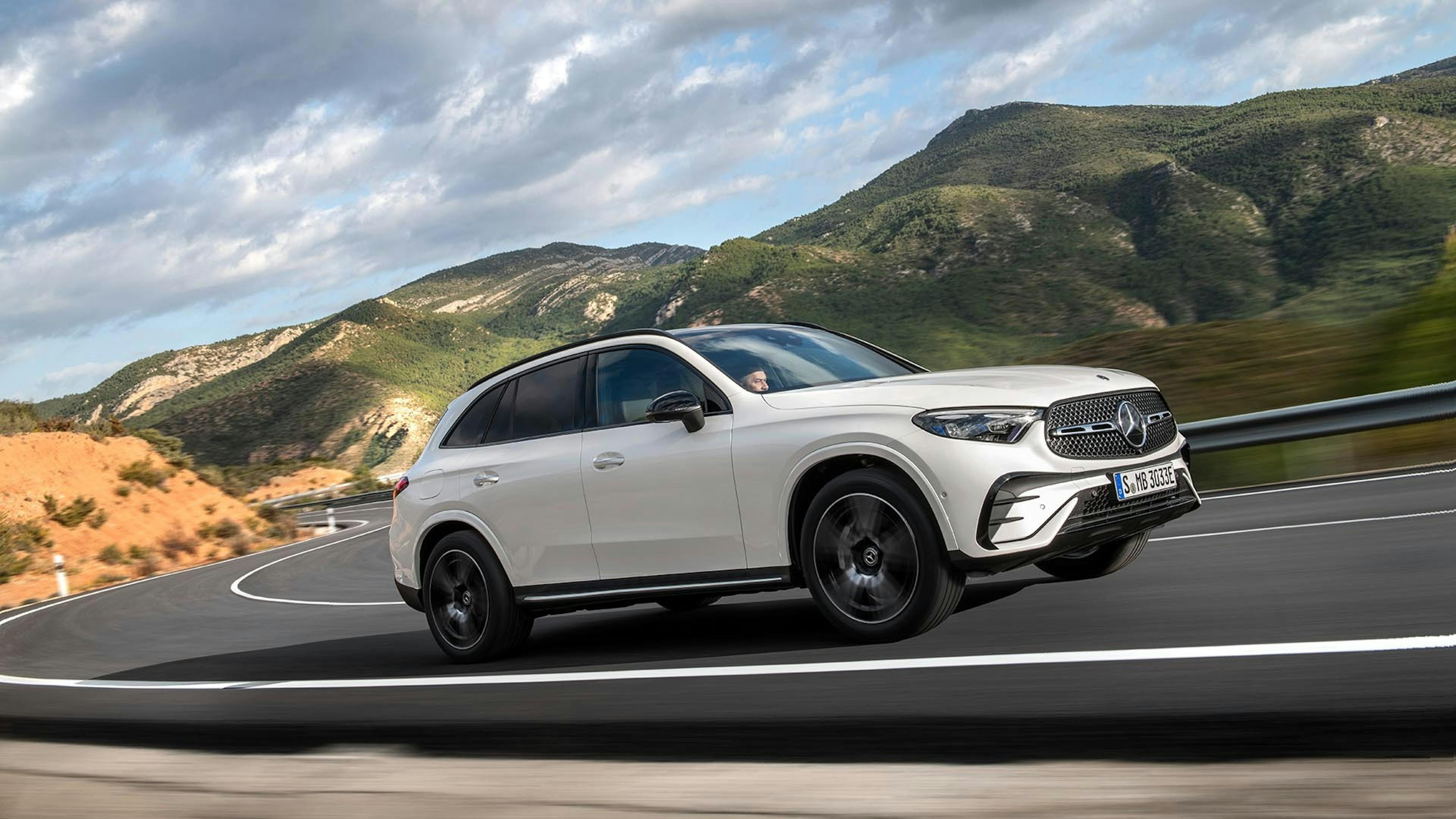 Ein weißer Mercedes GLC fährt auf einer kurvigen Landstraße.