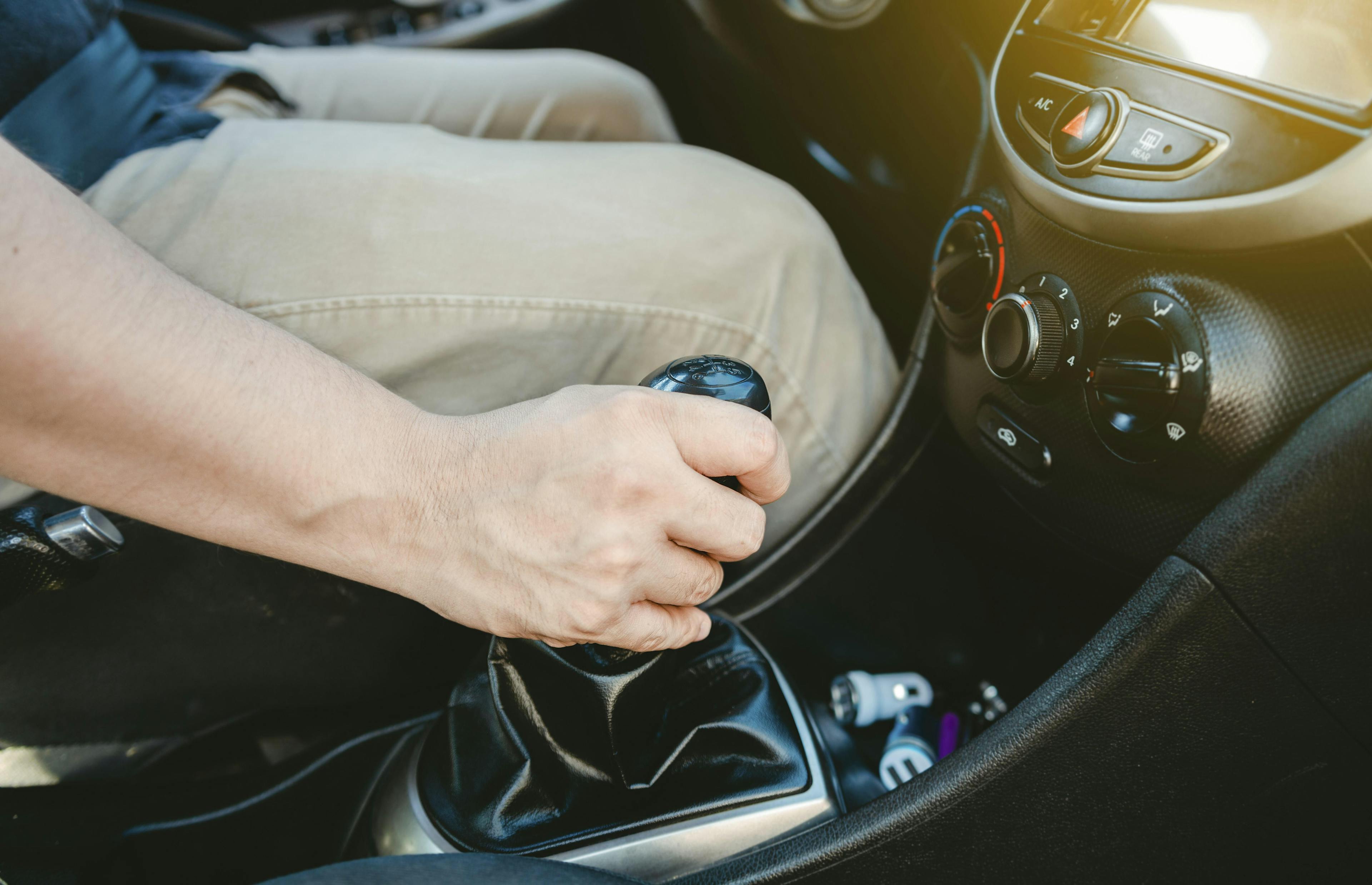 Nahaufnahme der Hand des Fahrers am Schalthebel eines Autos.