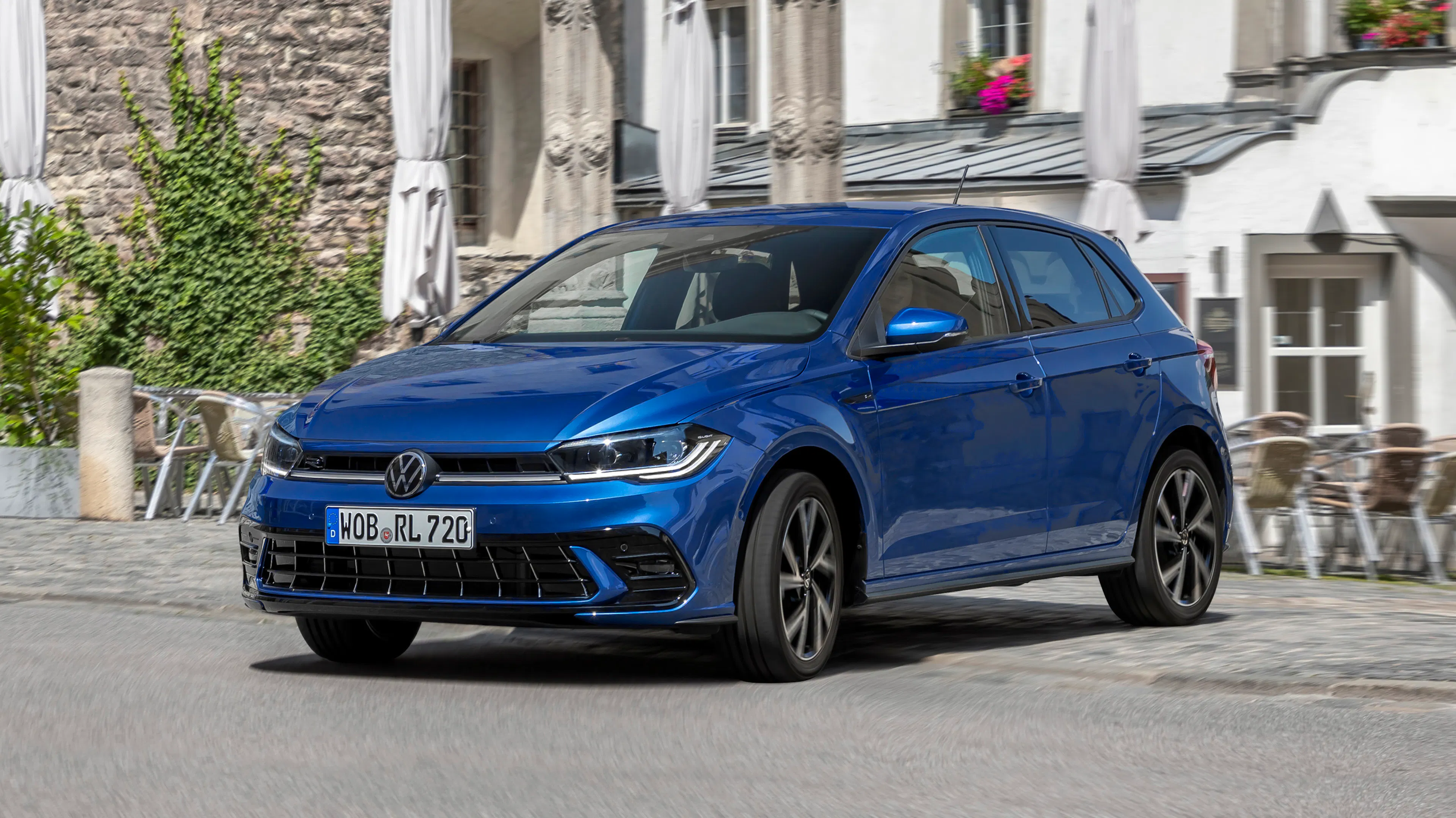Ein blauer VW Polo fährt durch eine Altstadt.