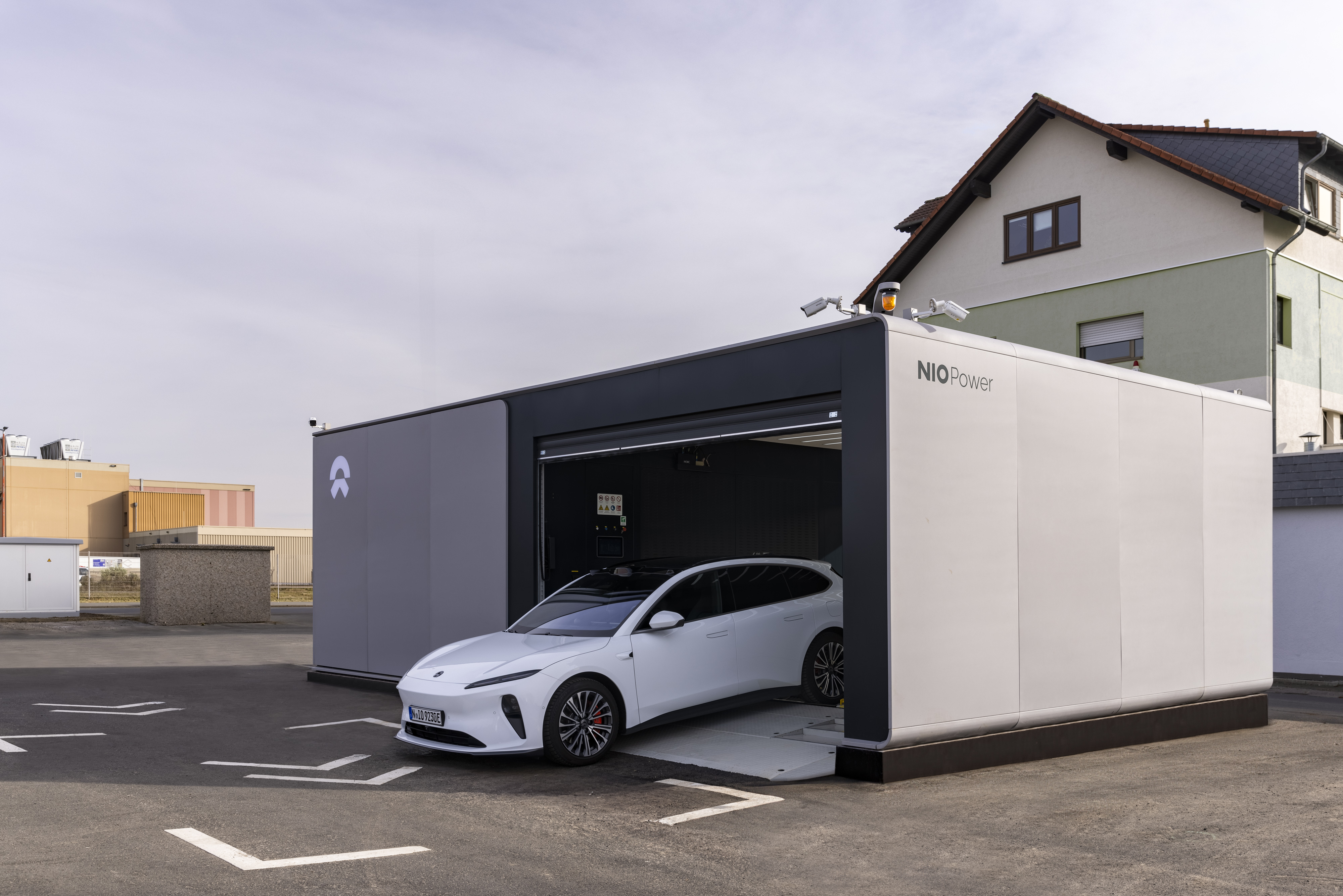 Ein weißer Nio ET5 Tourer fährt aus einer Batteriewechselstation in einem Container.