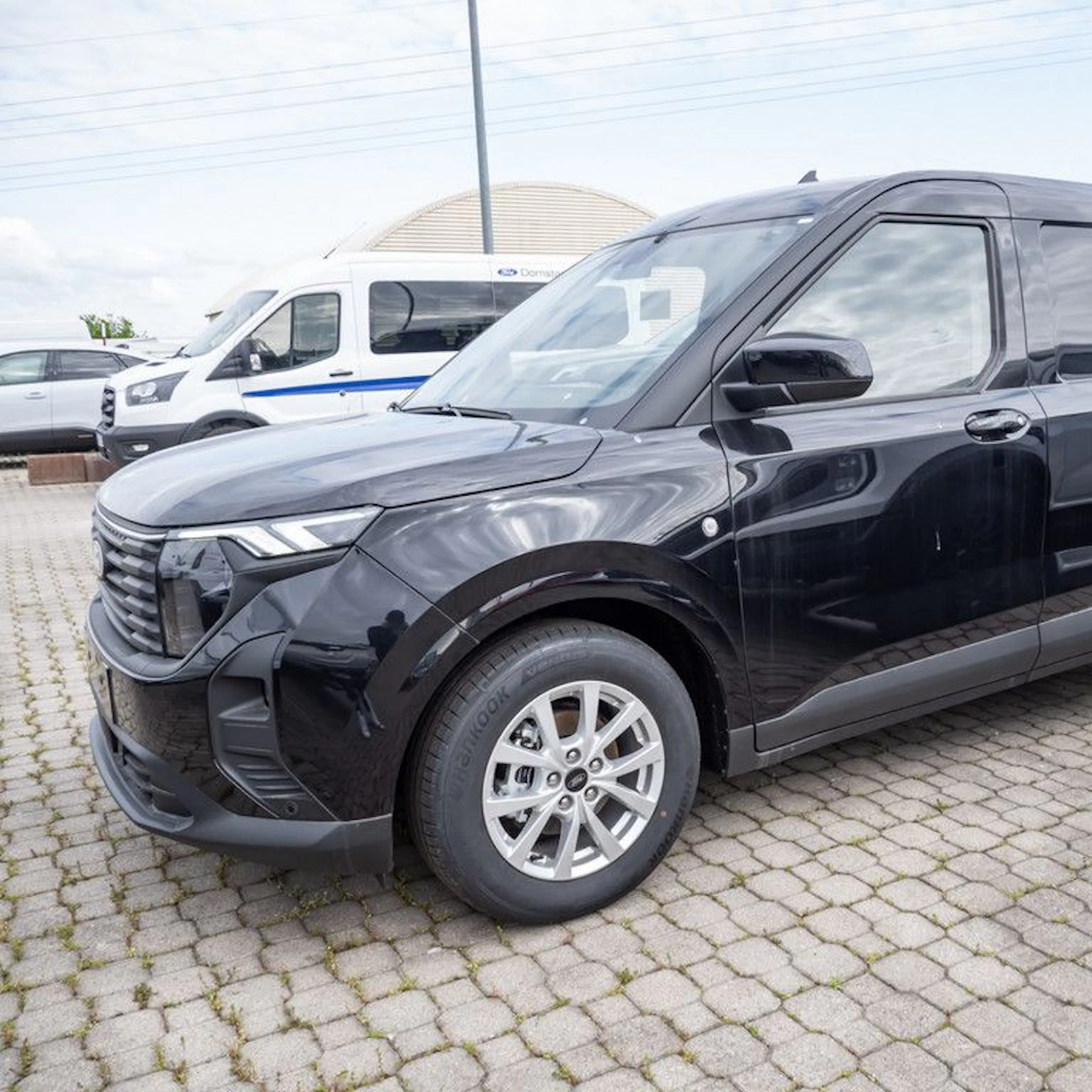 Ein schwarzer Ford Transit Courier parkt auf einem Hof.