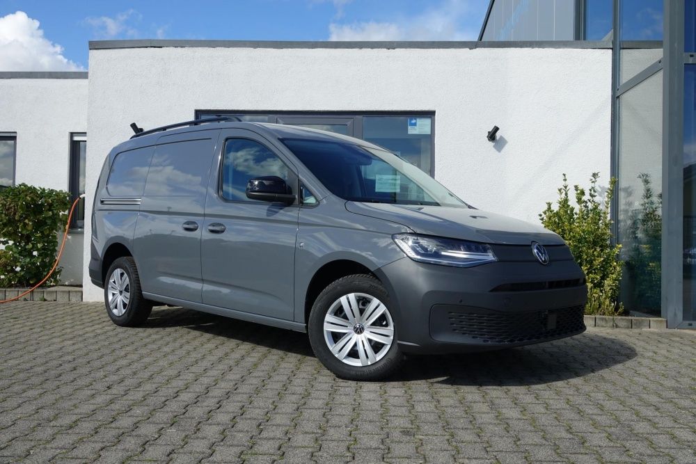 Ein grauer VW Caddy Cargo Maxi parkt auf einem Hof.