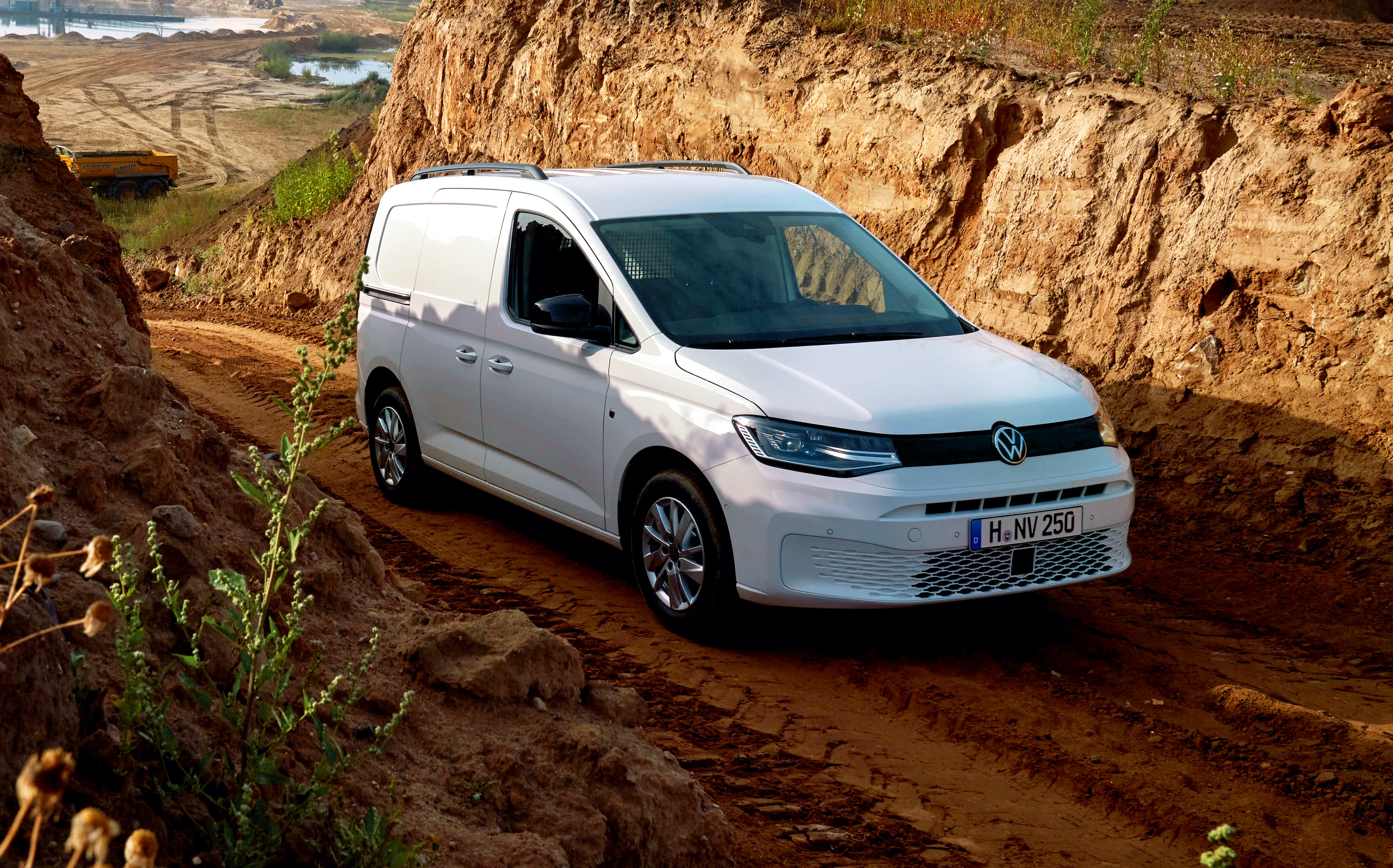 Ein weißer VW Caddy 4Motion steht in einem Tagebaubergwerk auf einer Matschpiste.
