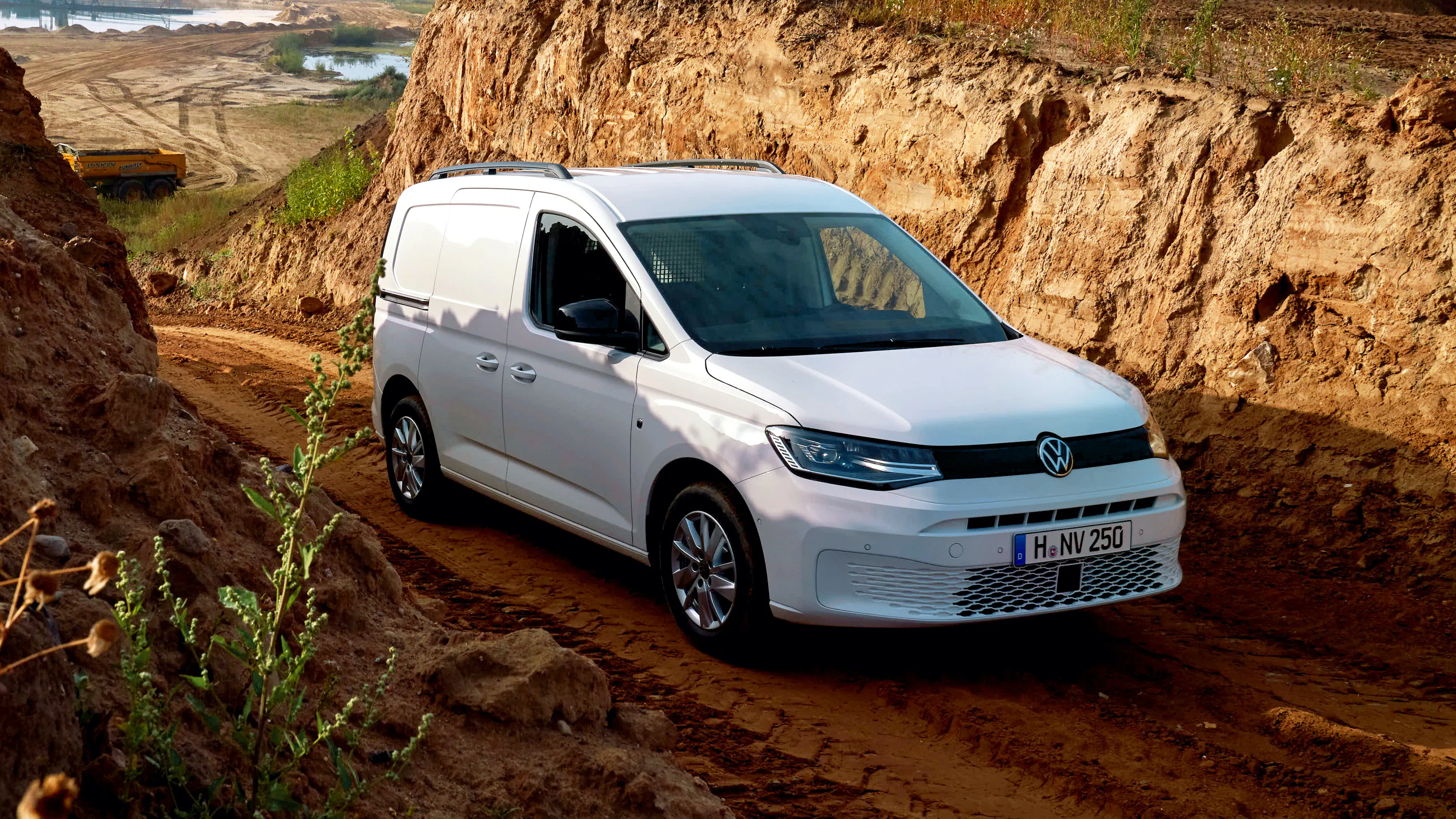 Ein weißer VW Caddy 4Motion steht in einem Tagebaubergwerk auf einer Matschpiste.