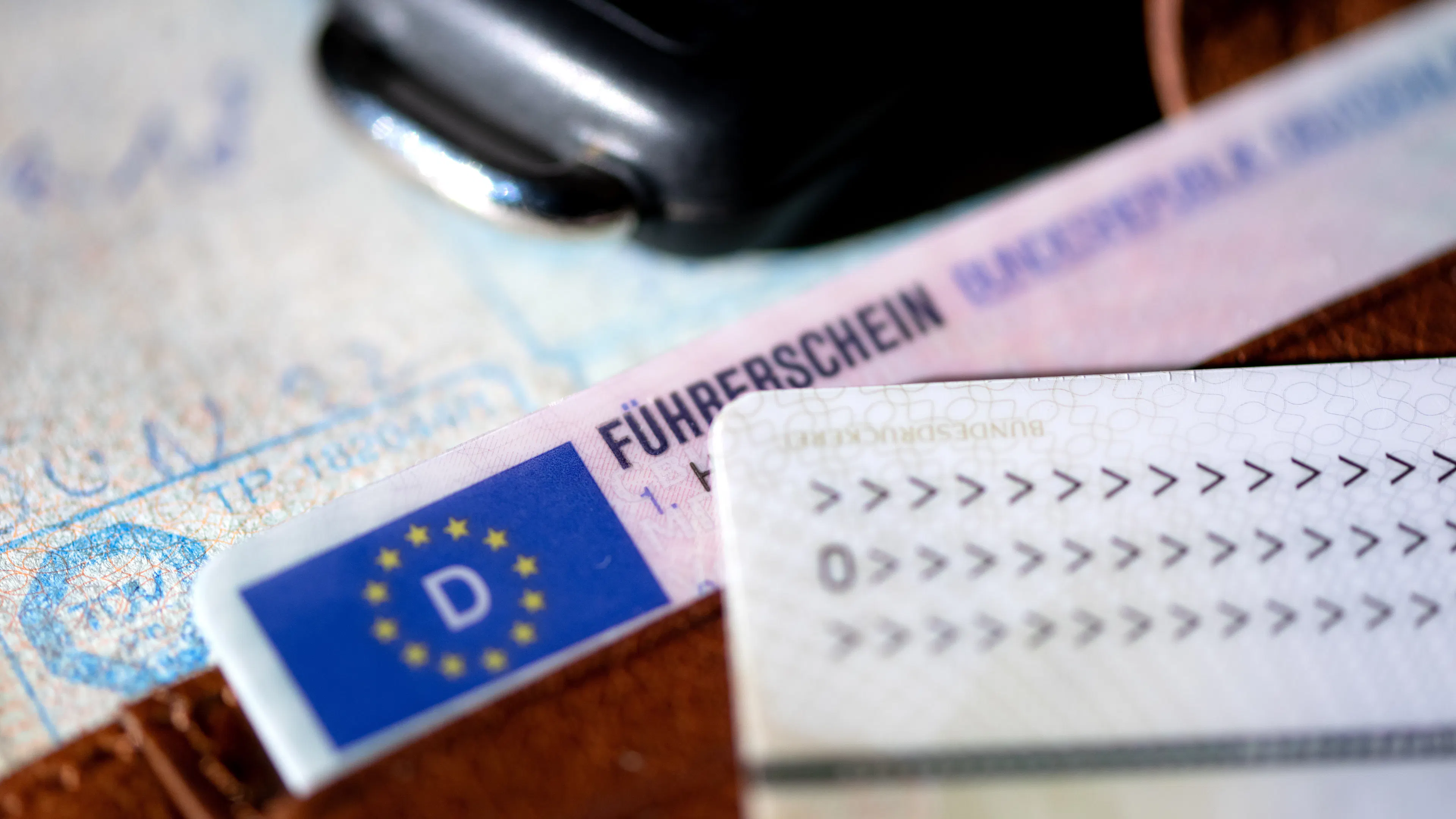 Mehrere Dokumente liegen auf einer Oberfläche, im Vordergrund ein deutscher Führerschein im neuen EU-Kartenformat, erkennbar am blauen EU-Feld mit dem „D“-Länderkürzel und Sternenkranz.