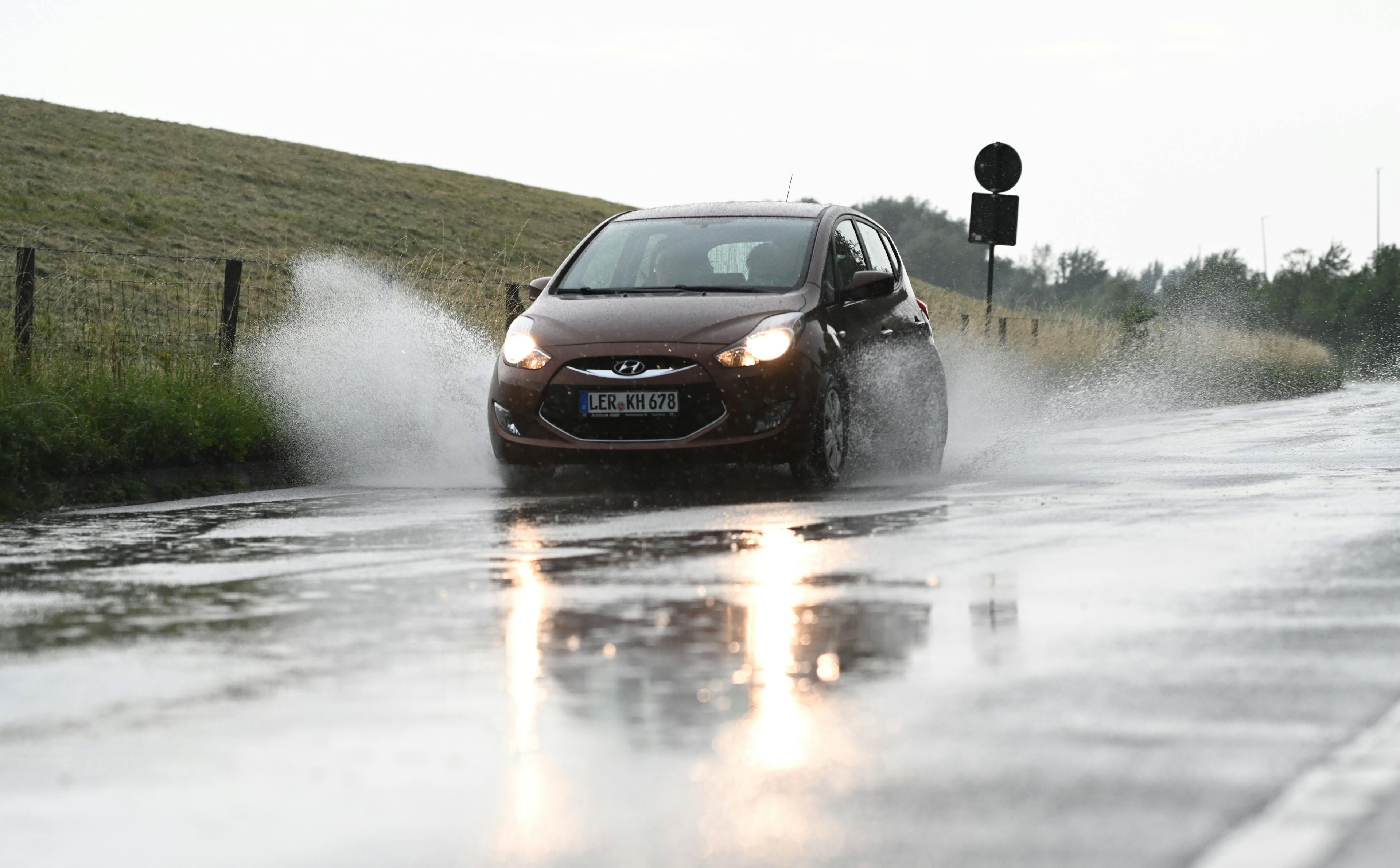 Ein Kleinwagen bremst auf einer nassen Landstraße scharf.

