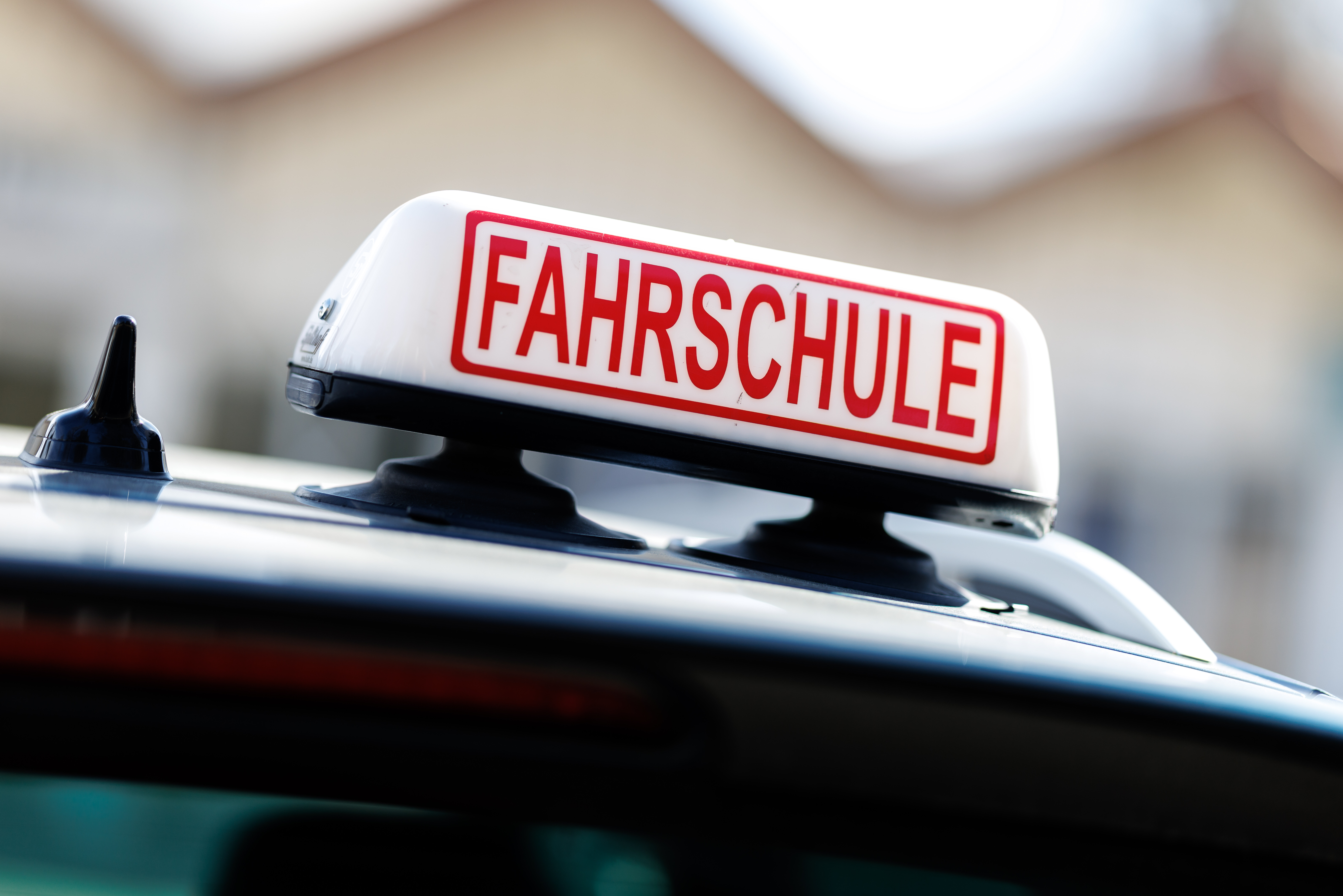 Ein Schild mit der Aufschrift "Fahrschule" ist auf einem Fahrschulfahrzeug zu sehen.