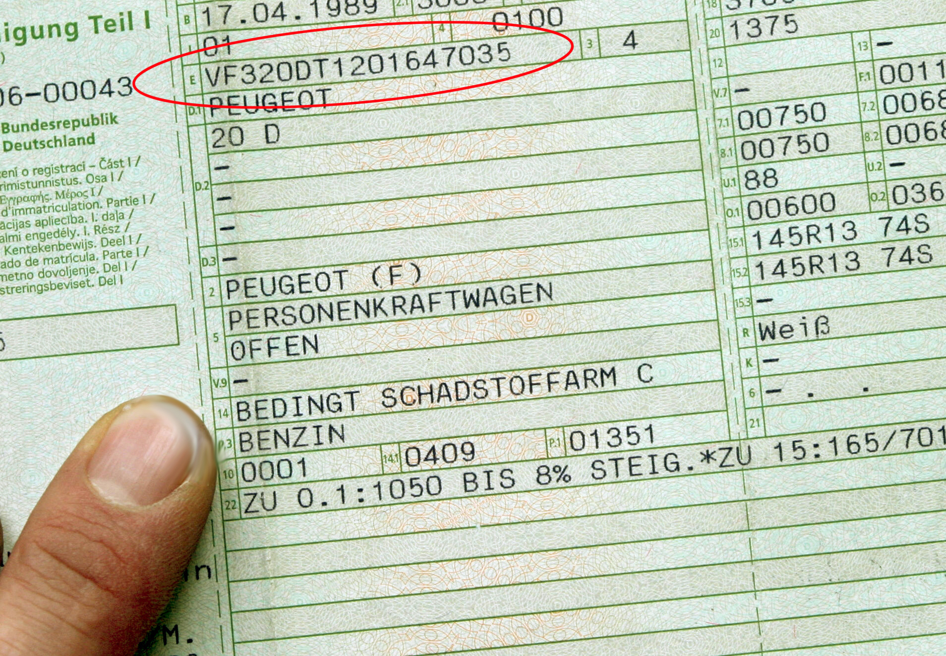 Jemand hält den Fahrzeugschein bzw. die Zulassungsbescheinigung Teil 1 in der Hand. Darauf ist neben weiteren Angaben auch die Fahrzeug-Identifizierungsnummer zu sehen.