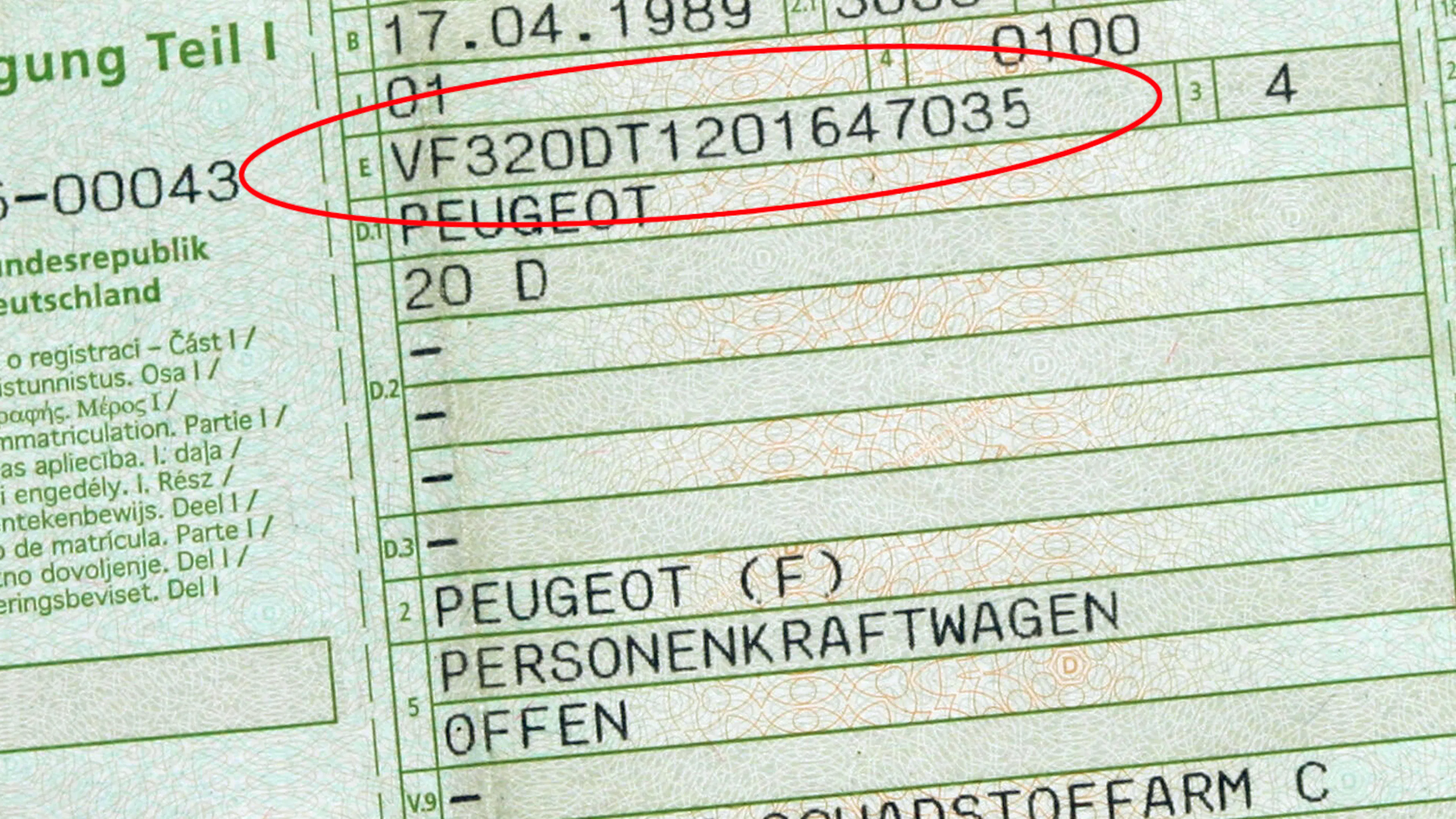 Jemand hält den Fahrzeugschein bzw. die Zulassungsbescheinigung Teil 1 in der Hand. Darauf ist neben weiteren Angaben auch die Fahrzeug-Identifizierungsnummer zu sehen.