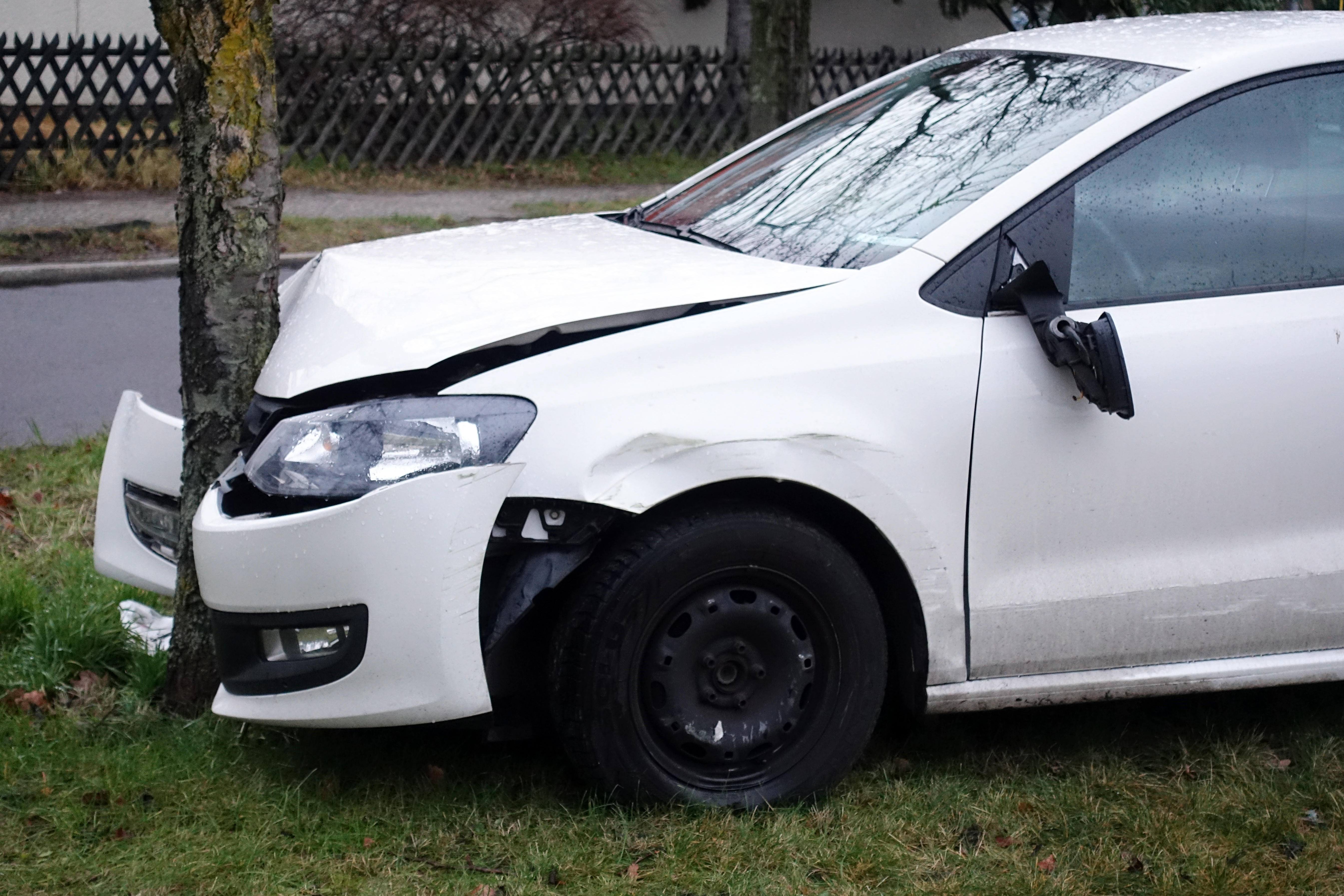 Ein weißes Auto wurde gegen einen Baum gefahren. An dem Wagen ist ein erheblicher Blechschaden entstanden.